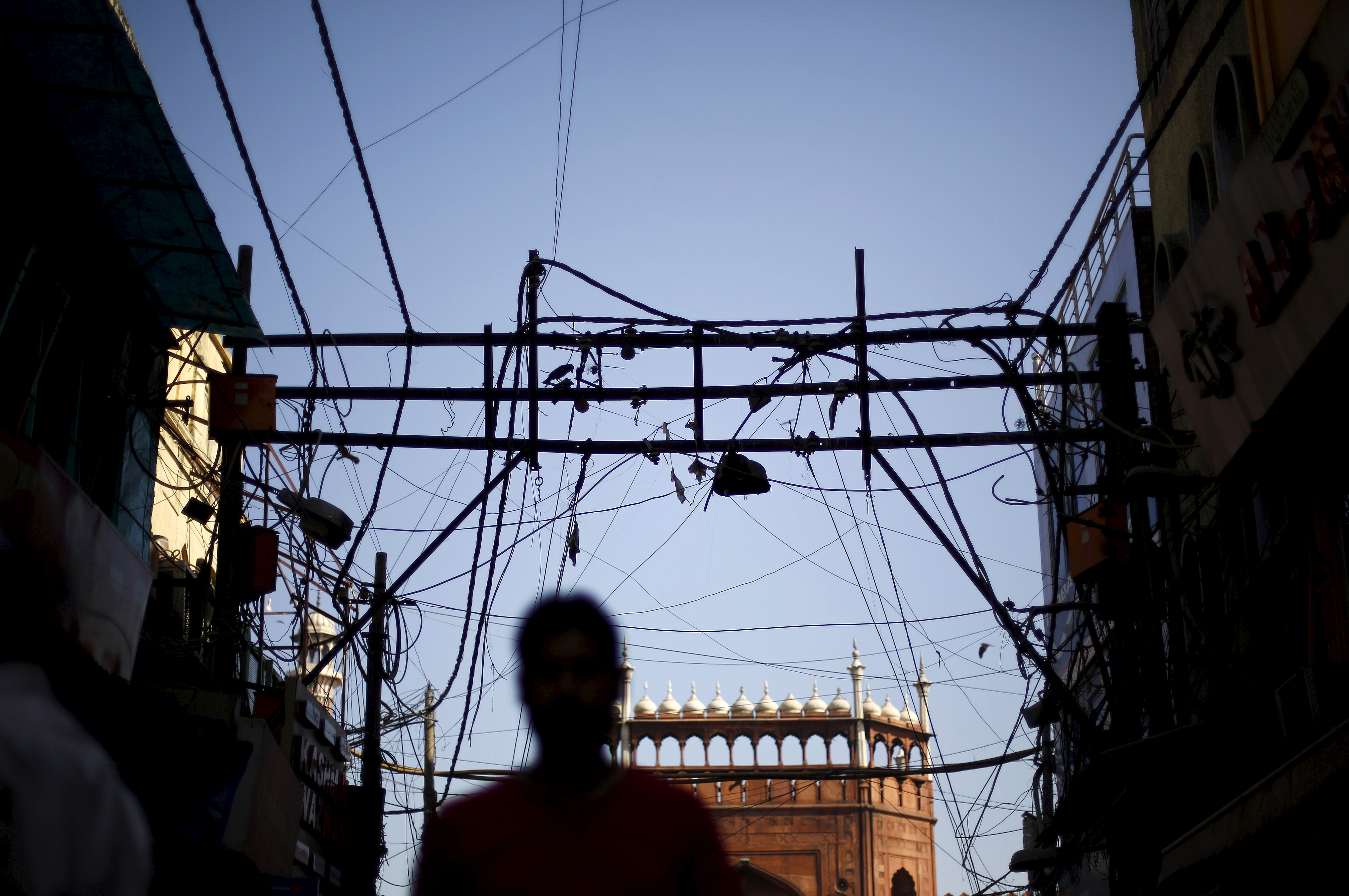 A man is silhouetted against the backdrop of Jama Masjid (Grand Mosque) as overhead power cables are seen in the old quarters of Delhi, India, September 10, 2015. REUTERS/Adnan Abidi
