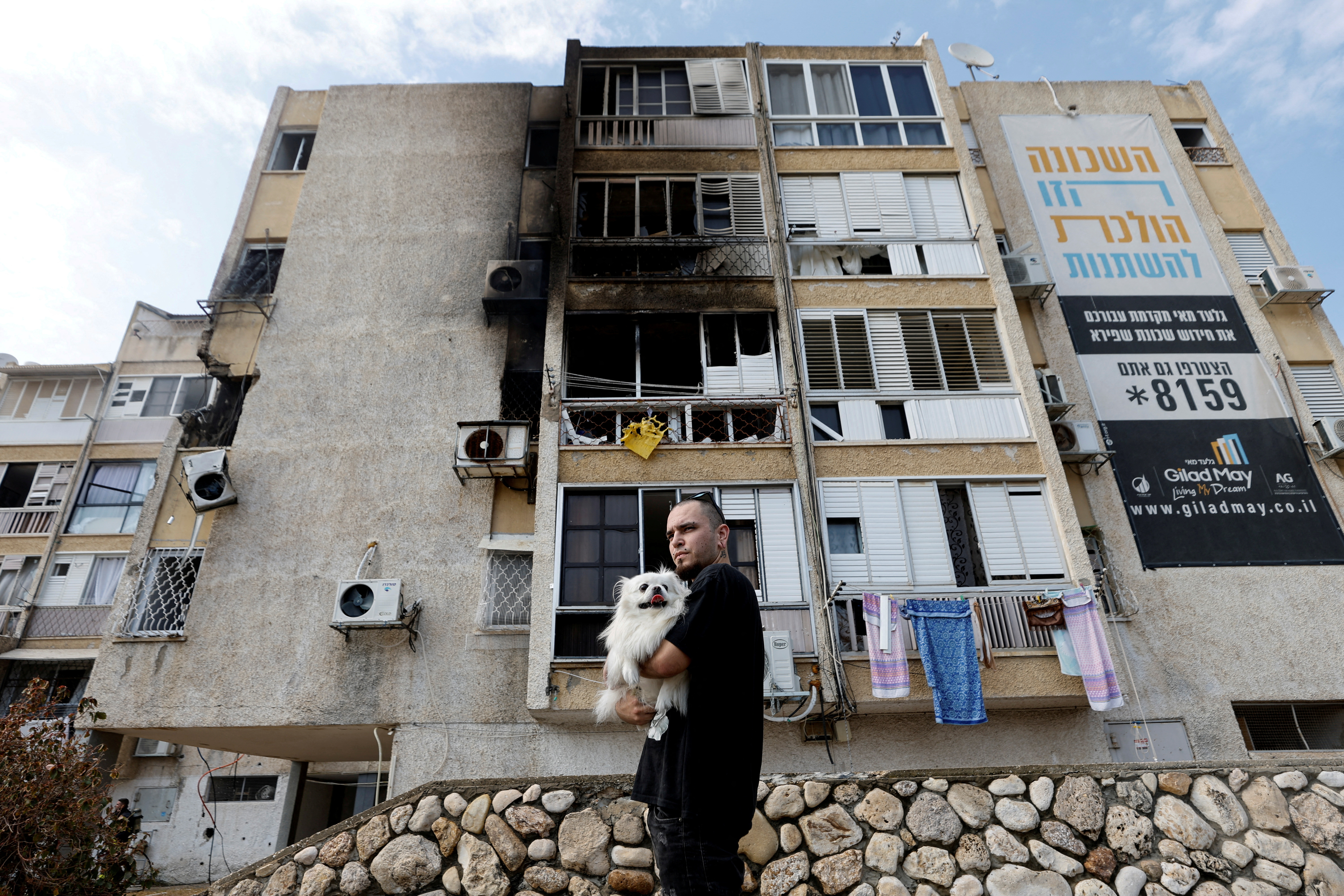 A man holds his dog after a rocket, launched from the Gaza Strip, landed in Ashkelon