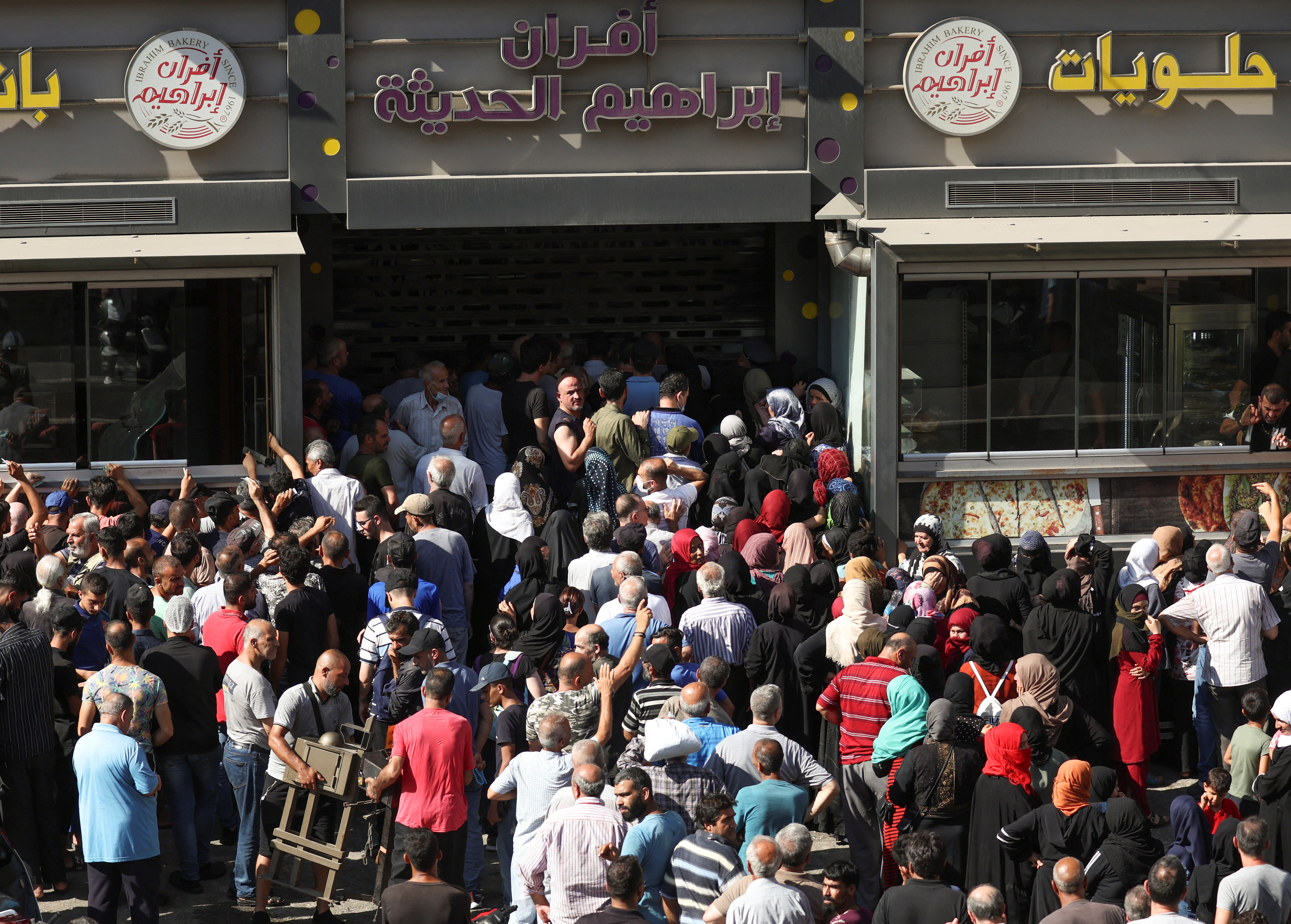 People queue to buy bread outside a bakery in Beirut