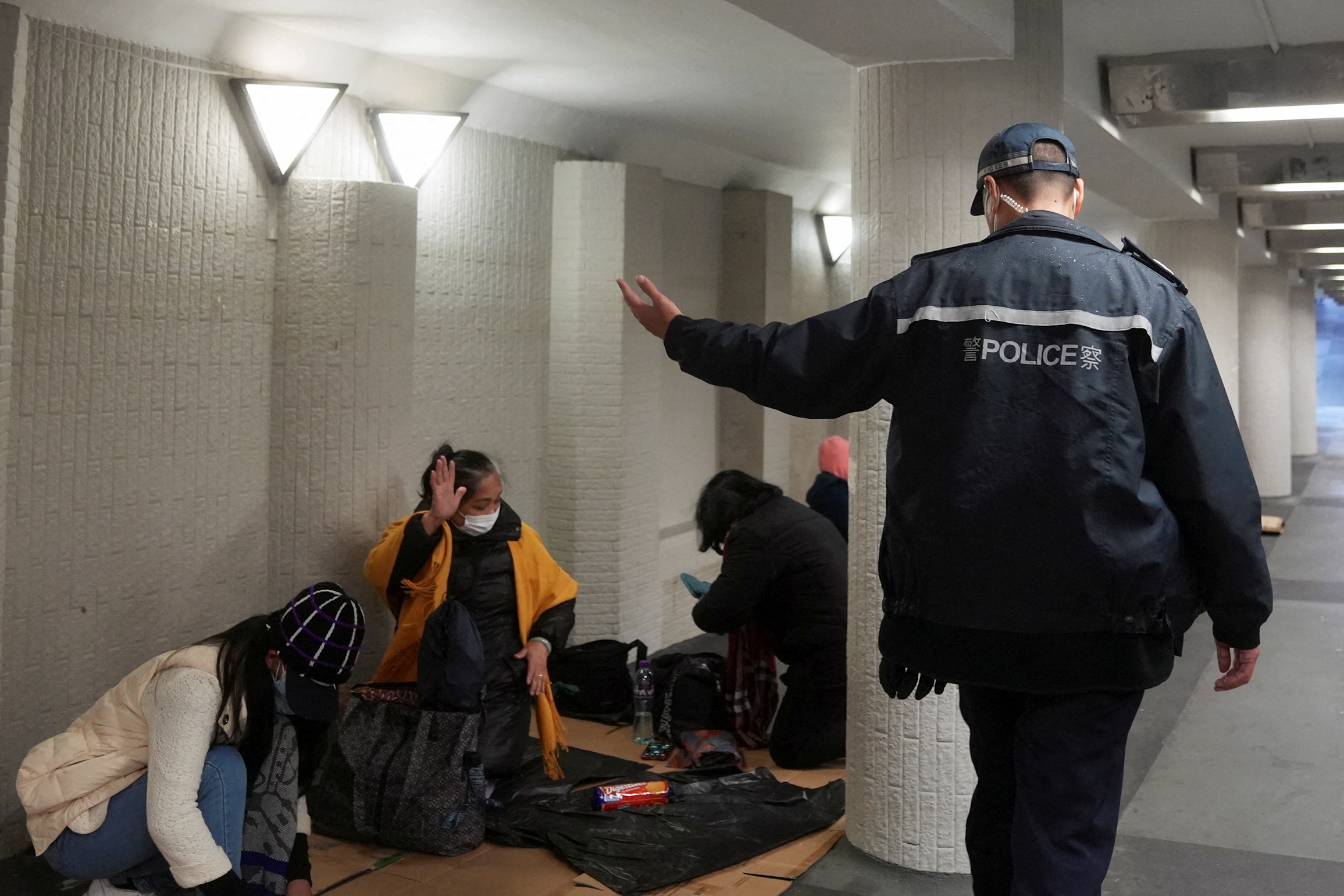 A police officer instructs domestic workers gathering on their rest day to leave, during a coronavirus disease (COVID-19) outbreak in Hong Kong, China