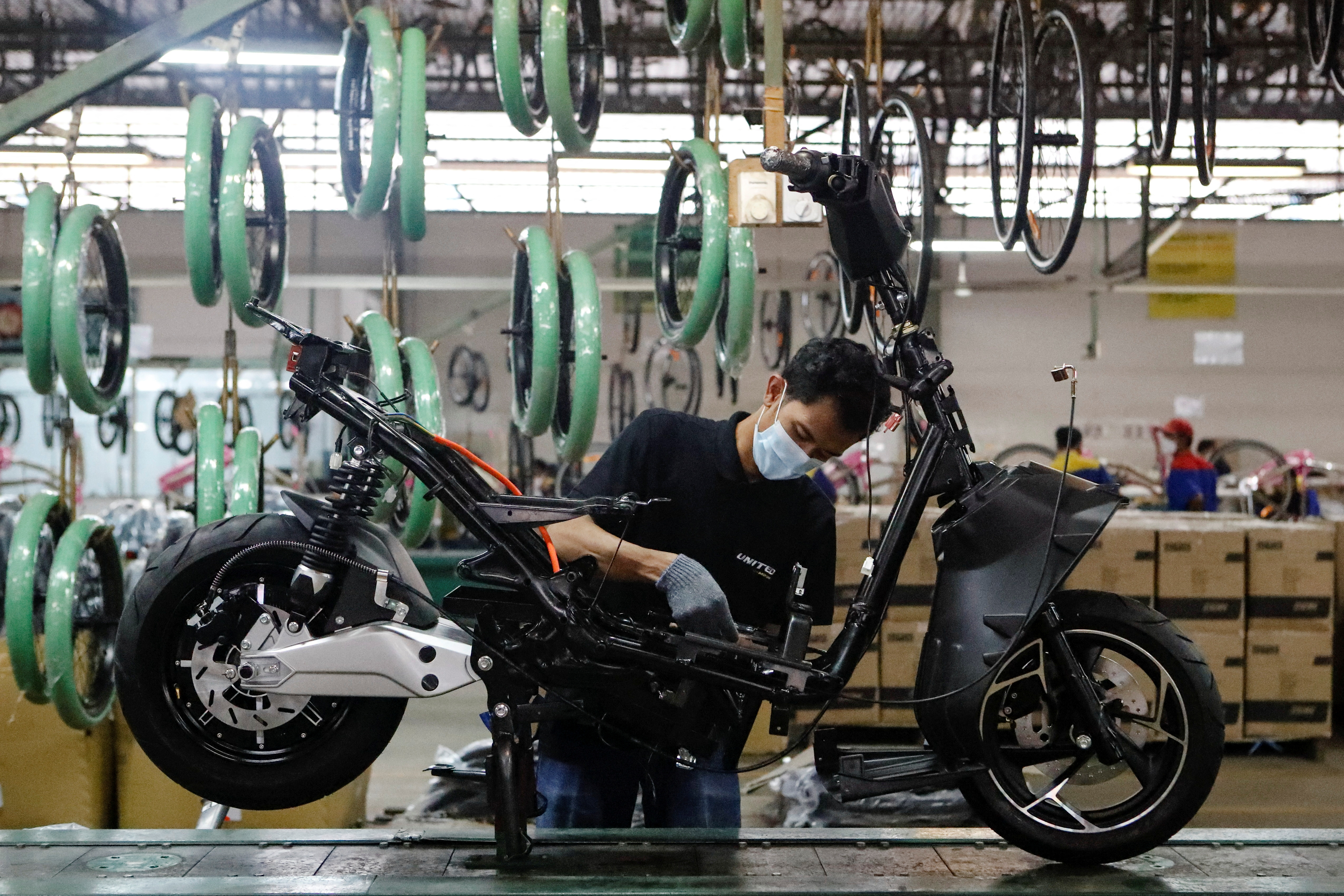 Employee works at the assembly line of an electric motorcycle at the United E-Motor factory in Bogor