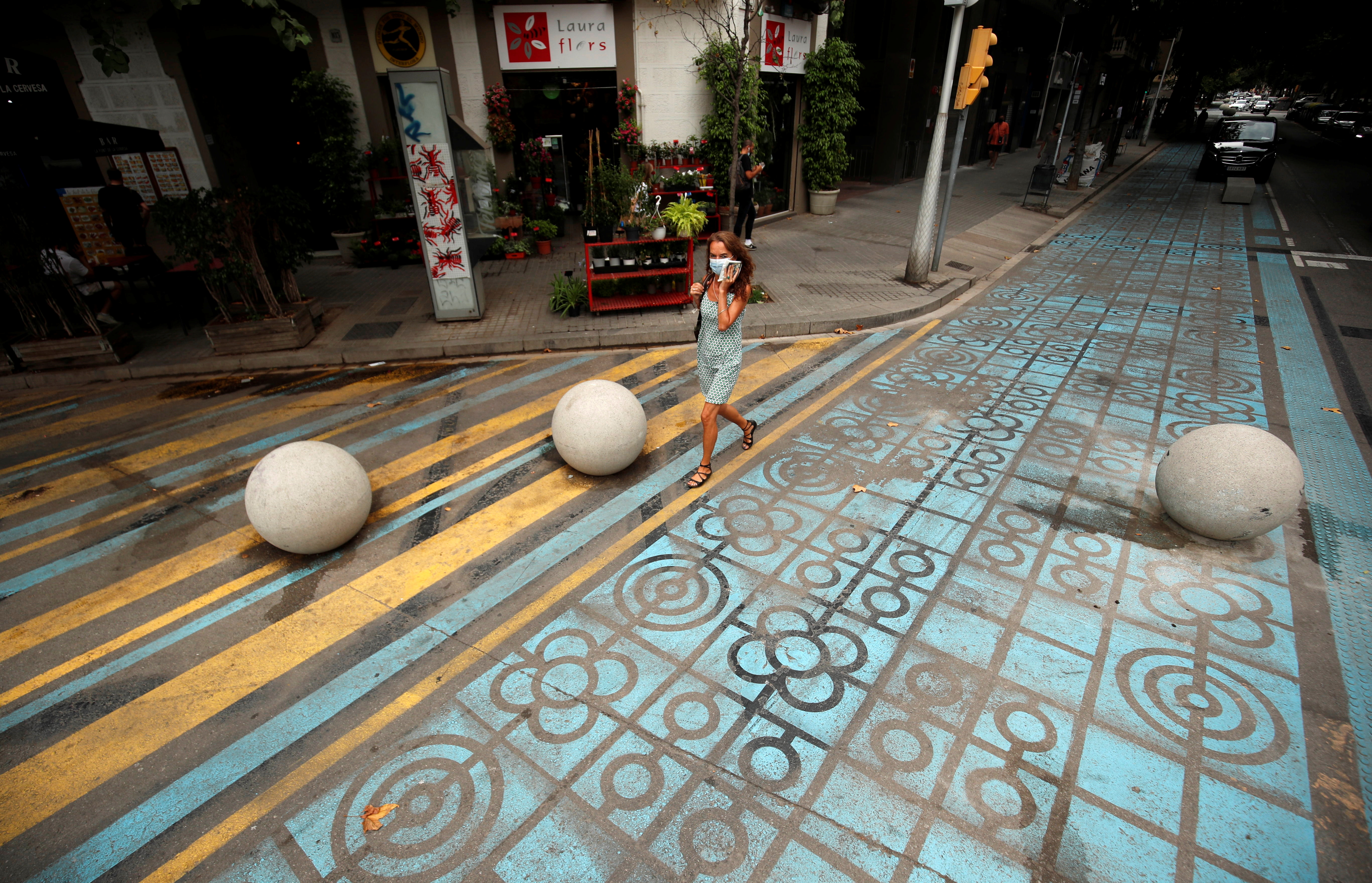 Woman walks by a pedestrian zone painted in blue and yellow at a junction in Barcelona