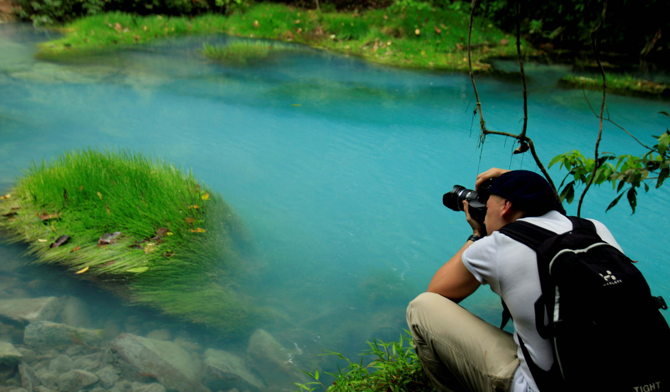 A tourist takes pictures of a blue lagoon at Tenorio Volcano National Park in Upala March 18, 2008. The blue color of the lagoon, formed from chemical reactions of calcium carbonate and sulfur, is surrounded by an amazing rainforest that constitutes 12,819 hectares of this park. REUTERS/Juan Carlos Ulate (COSTA RICA)