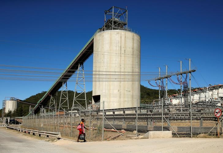 A woman walks past Anglo American Platinum's Unki mine in Shurugwi