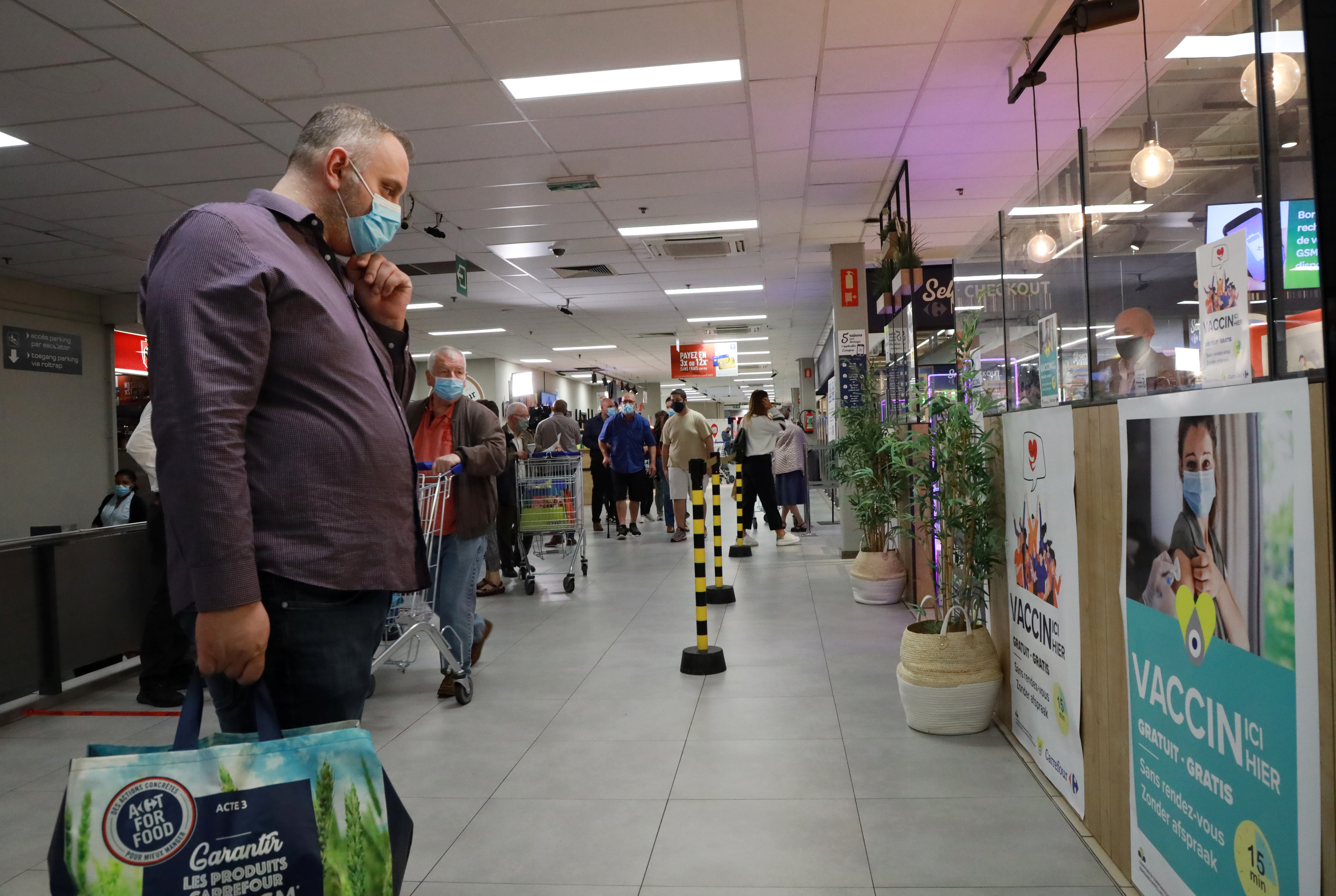 A shopper, wearing a protective face masks, looks at a poster for a coronavirus disease (COVID-19) vaccination centre installed inside a supermarket in Brussels, Belgium, August 30, 2021. REUTERS/Bart Biesemans