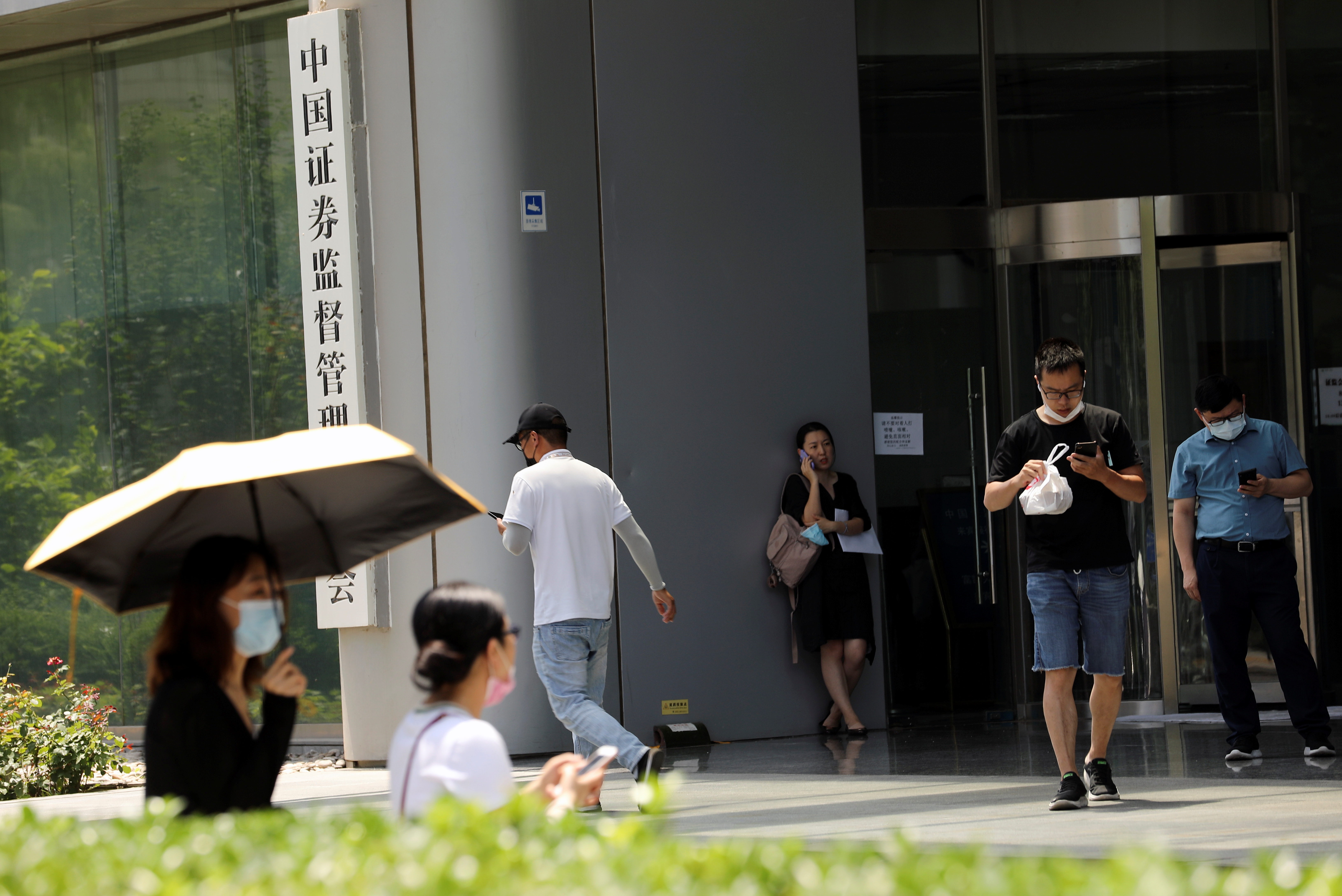 People walk past the China Securities Regulatory Commission (CSRC) sign at its building on the Financial Street in Beijing, China July 9, 2021. REUTERS/Tingshu Wang