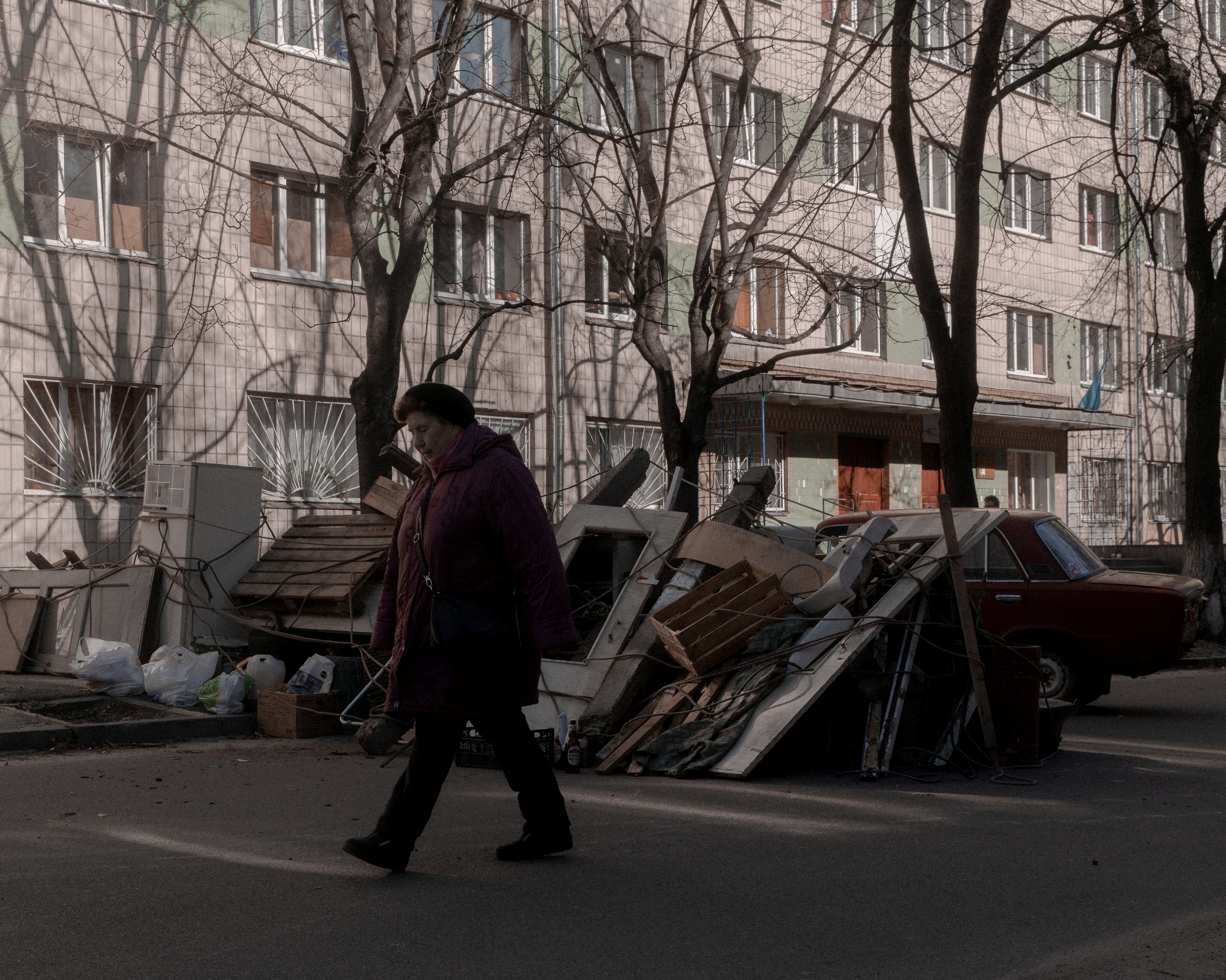 A woman walks past a street barricade in Kyiv