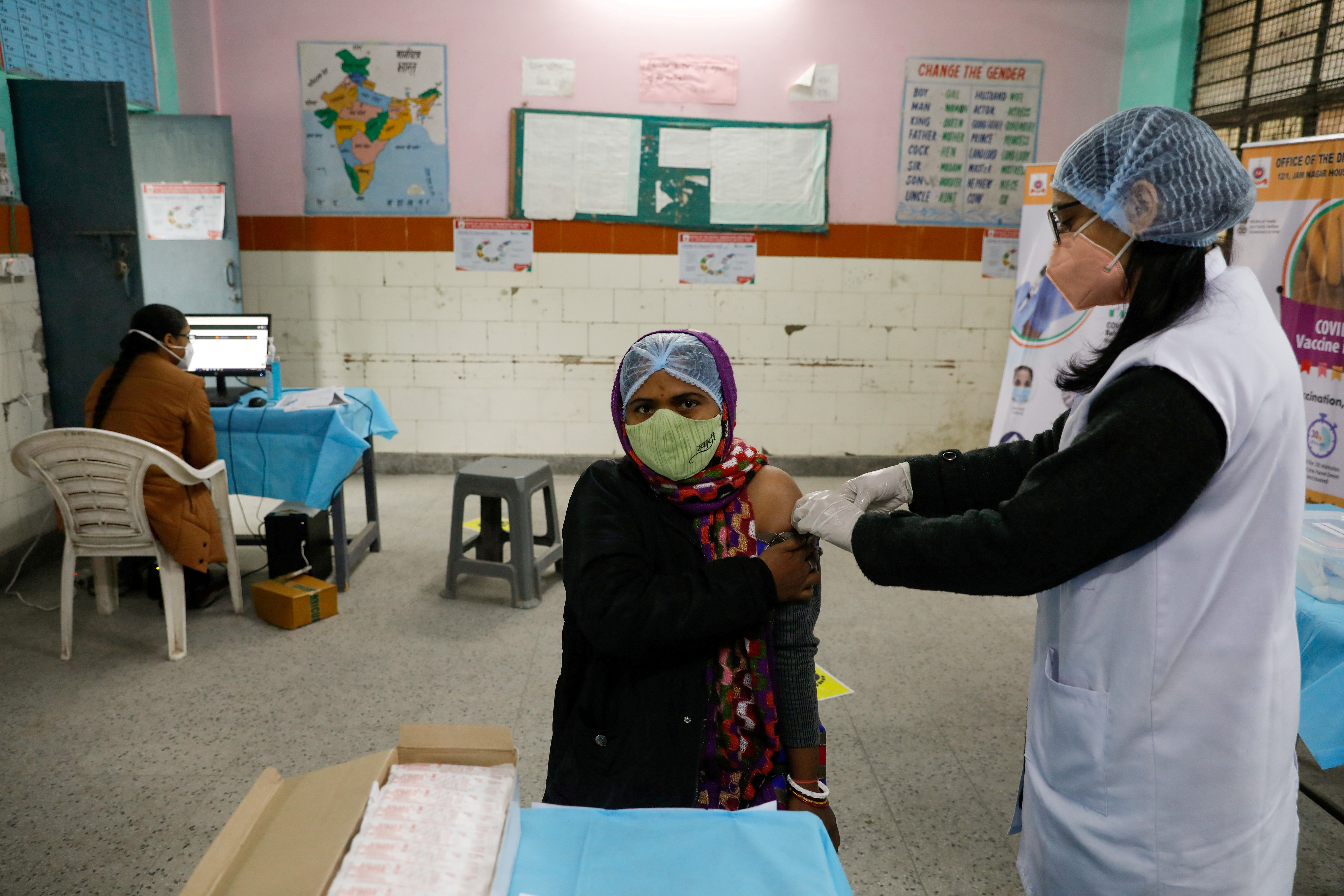 A health worker and a volunteer take part in a nationwide trial run of coronavirus disease (COVID-19) vaccine delivery systems, inside a school, which has been converted into a temporary vaccination centre, in New Delhi