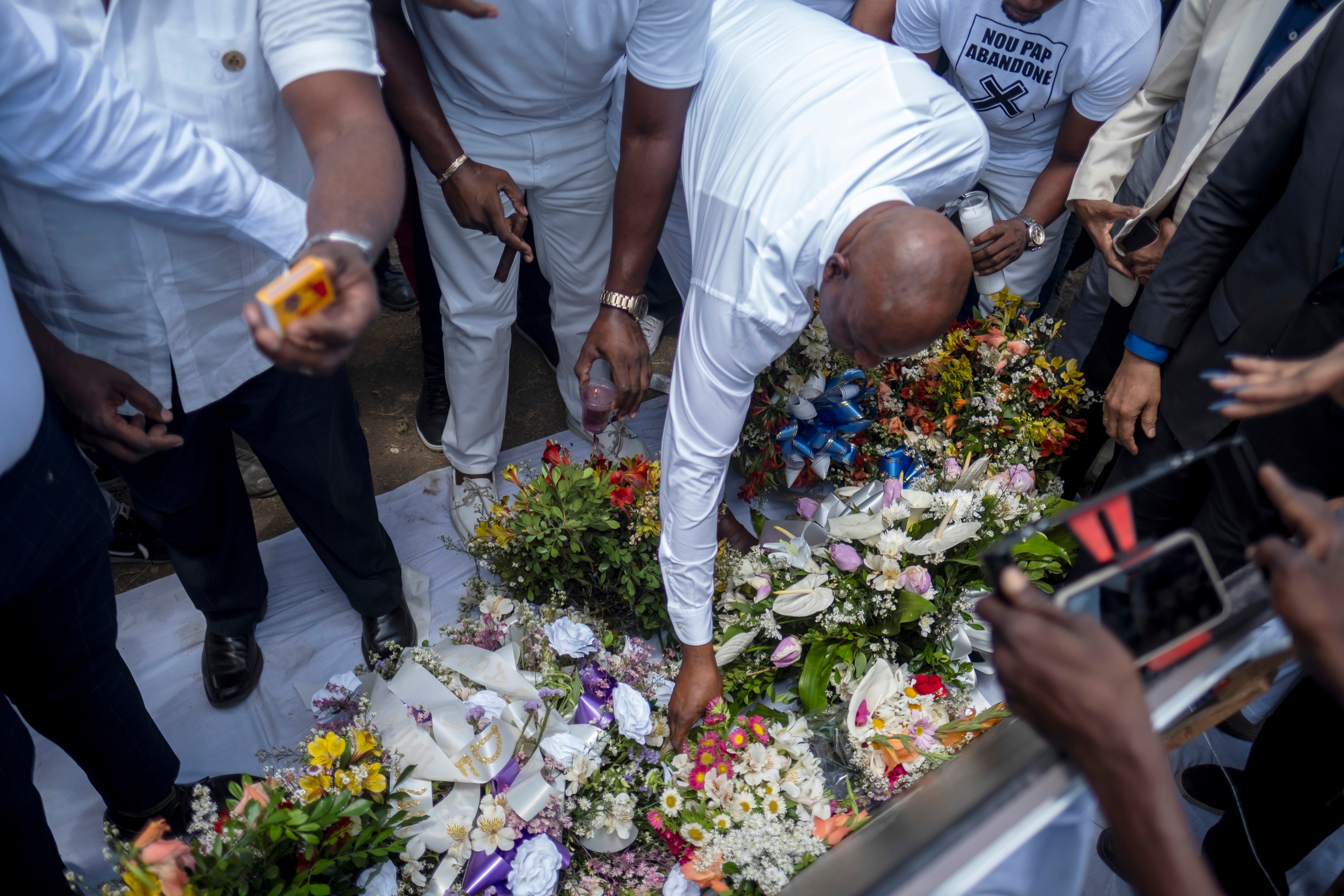 People place flowers at a memorial outside the Presidential Palace in memory of President Jovenel Moise, a week after his assassination, in Port-au-Prince, Haiti July 14, 2021. REUTERS/Ricardo Arduengo