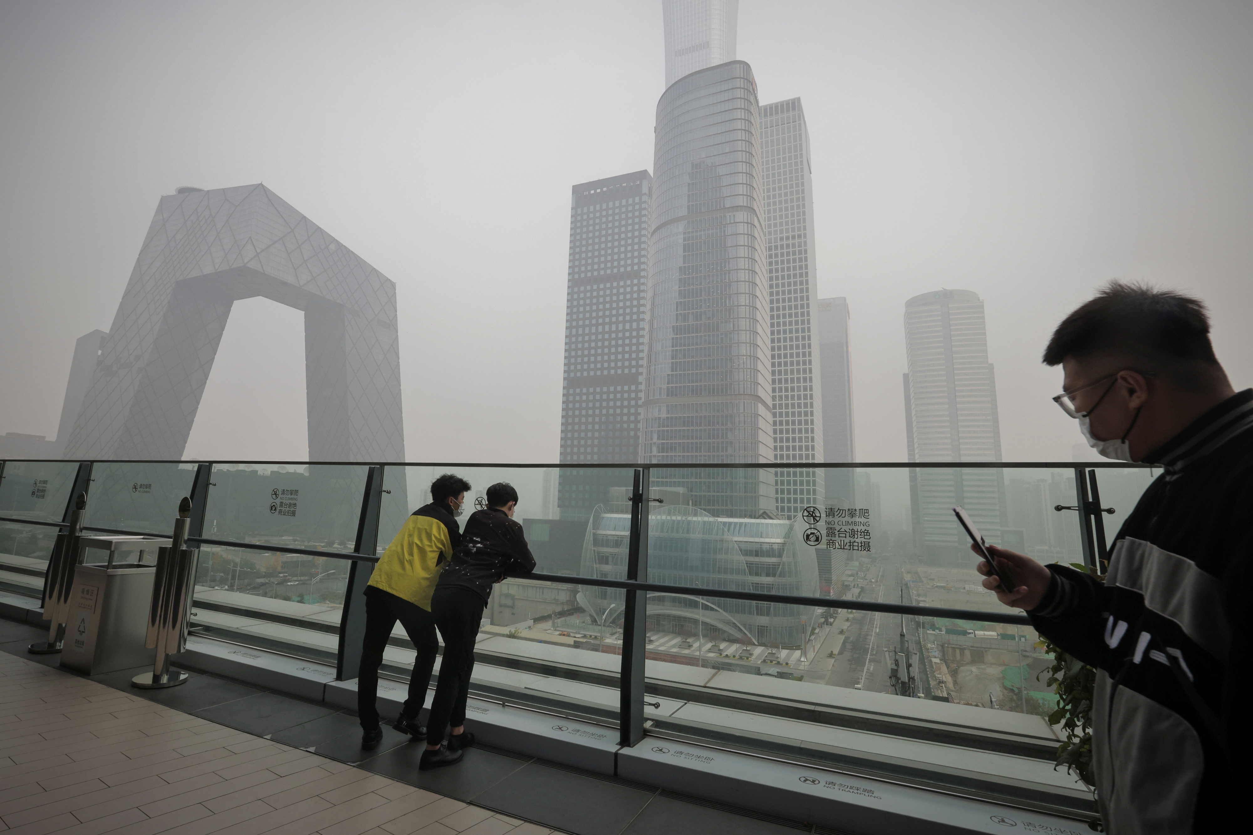 People overlook the skyline of the Central Business District on a polluted day in Beijing