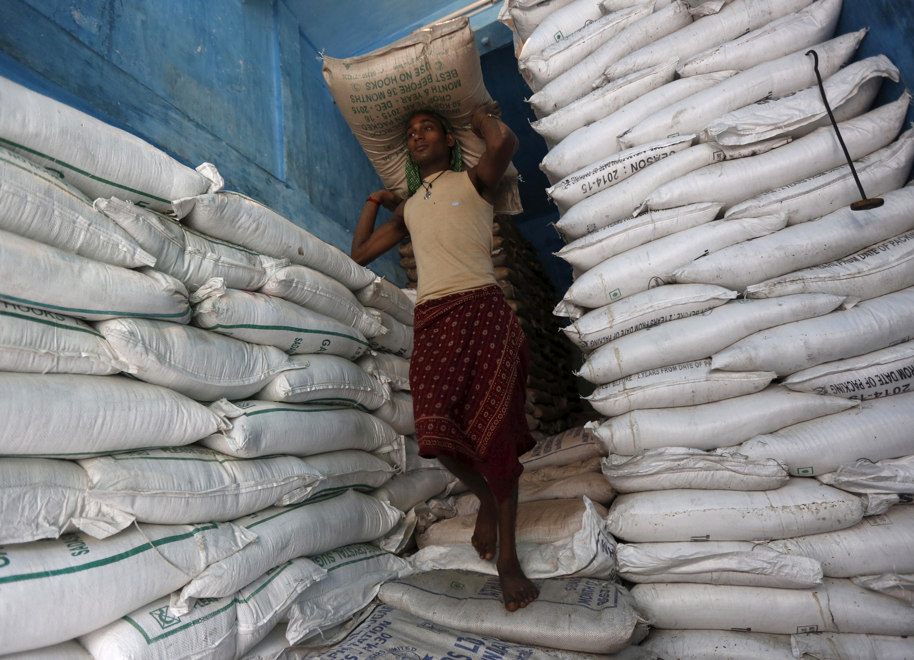 A labourer carries a sack filled with sugar in a store at a wholesale market in Kolkata