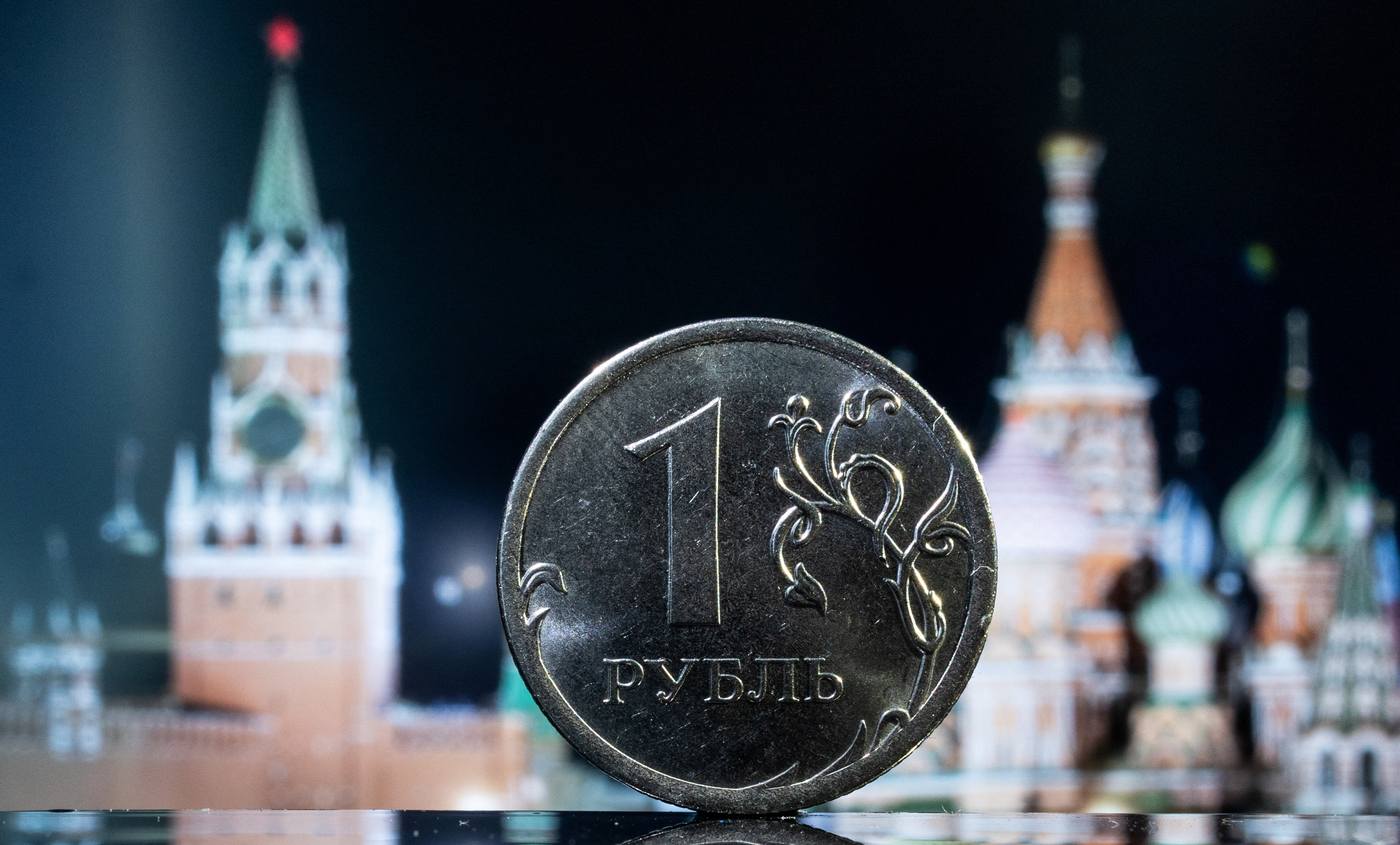 A Russian one rouble coin is pictured in front of a monitor showing the Kremlin's tower