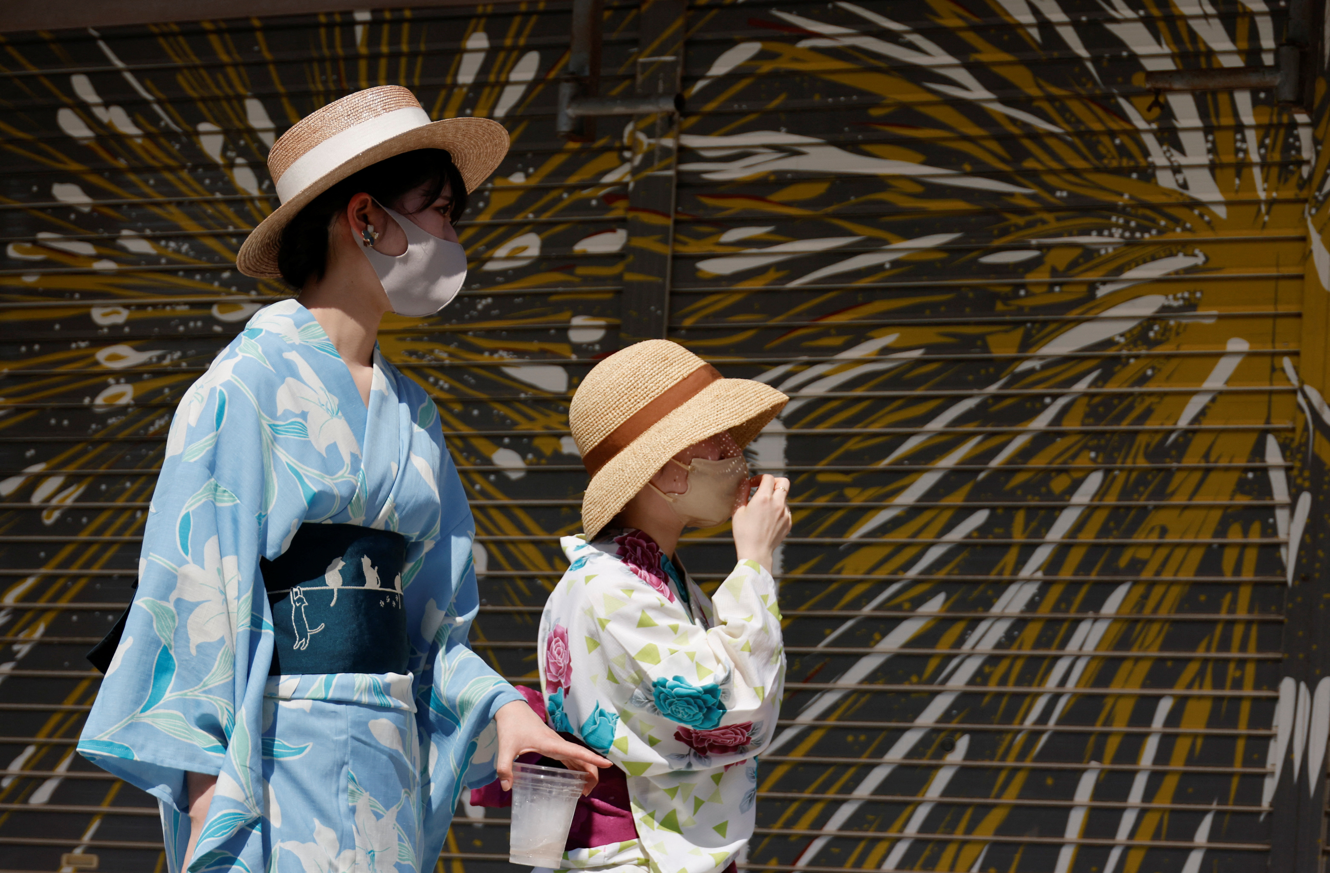 Women wearing summer kimonos and straw hats walk on the street as Japanese government issues warning over possible power crunch due to heatwave at Asakusa district in Tokyo