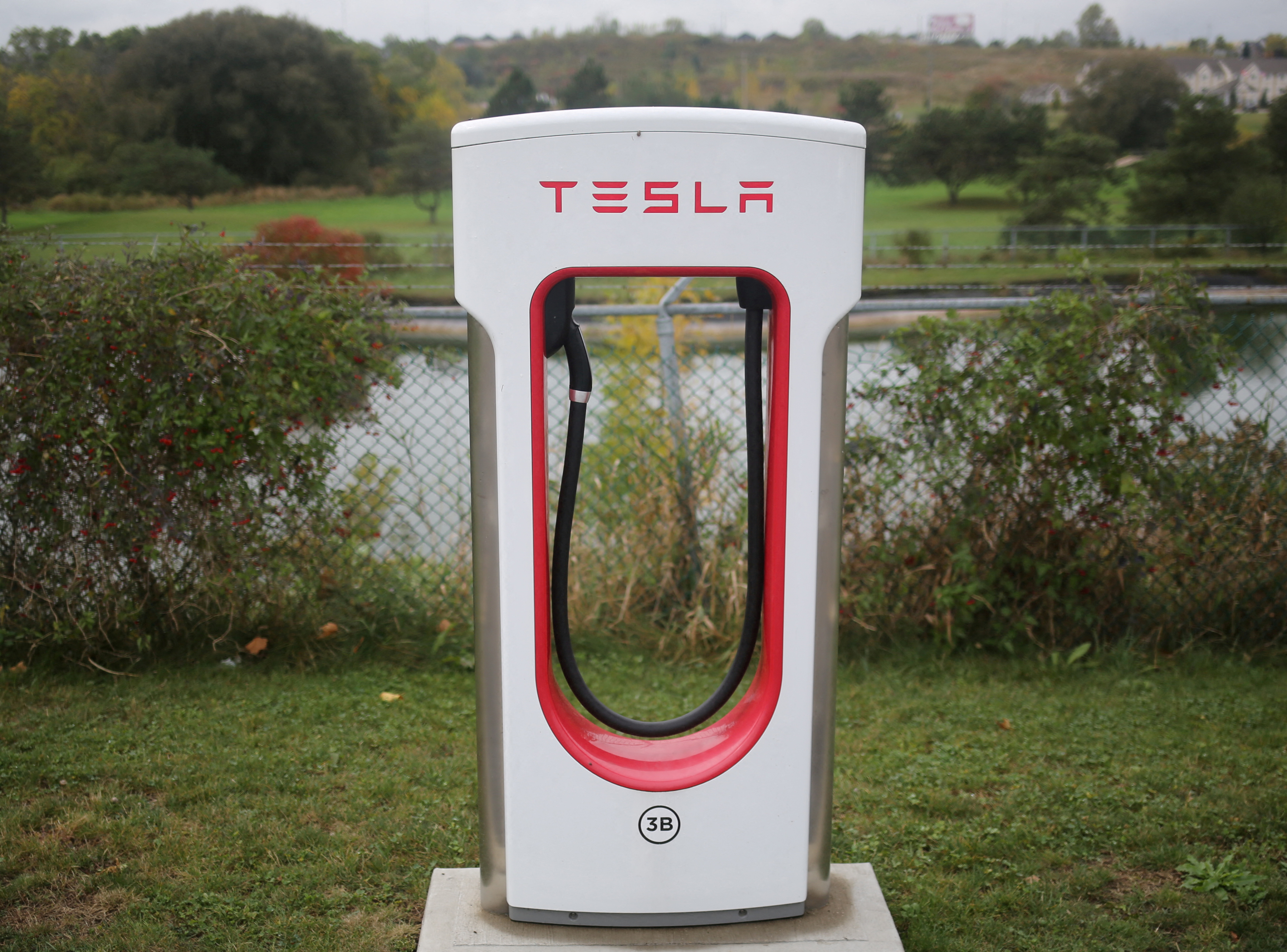 A Tesla electric vehicle charger is seen at the edge of a parking lot in Kitchener