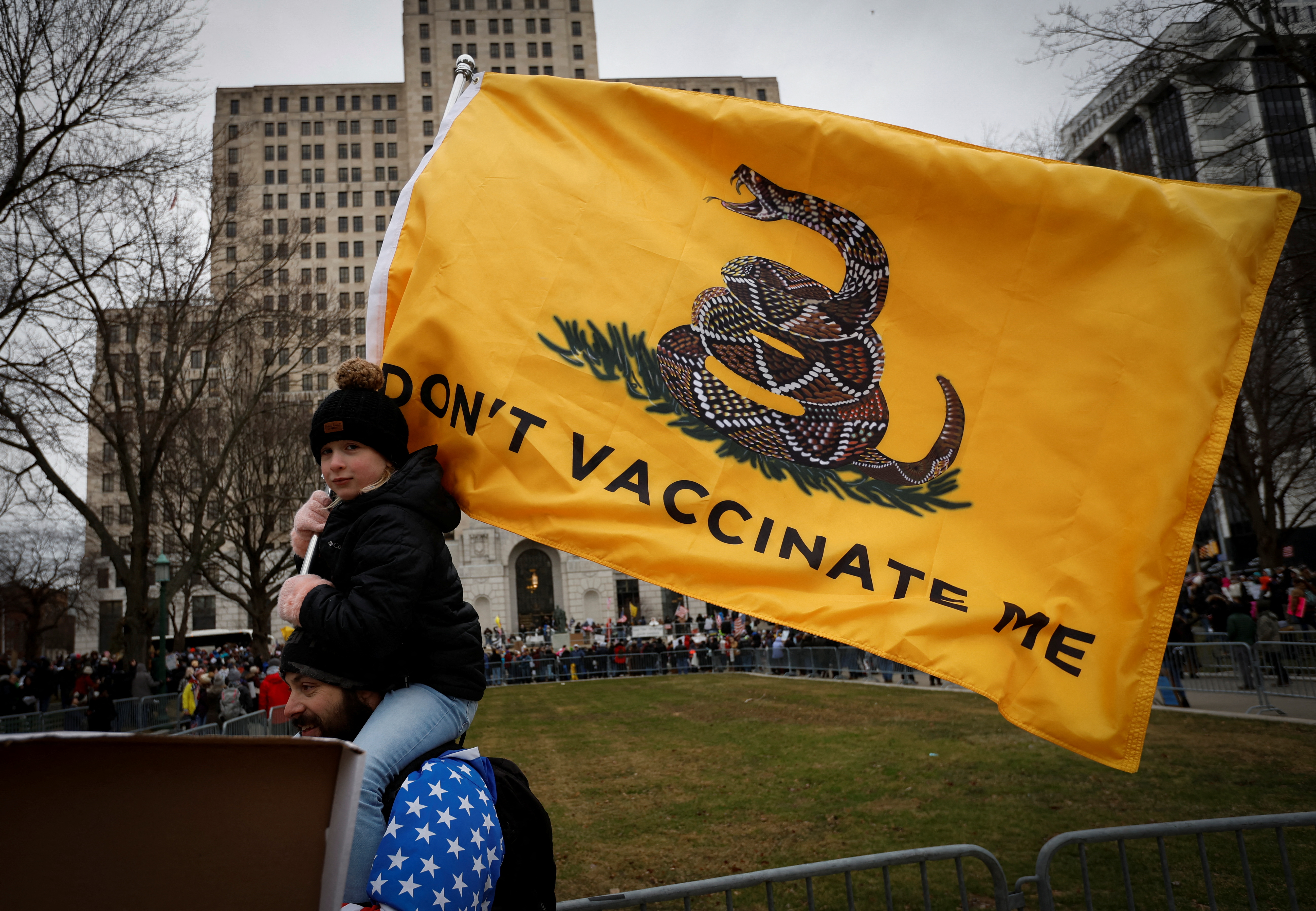 A child on a man's shoulders holds a banner at a rally against mandates for the vaccines against the coronavirus disease (COVID-19) outside the New York State Capitol in Albany, New York, U.S., January 5, 2022. REUTERS/Mike Segar