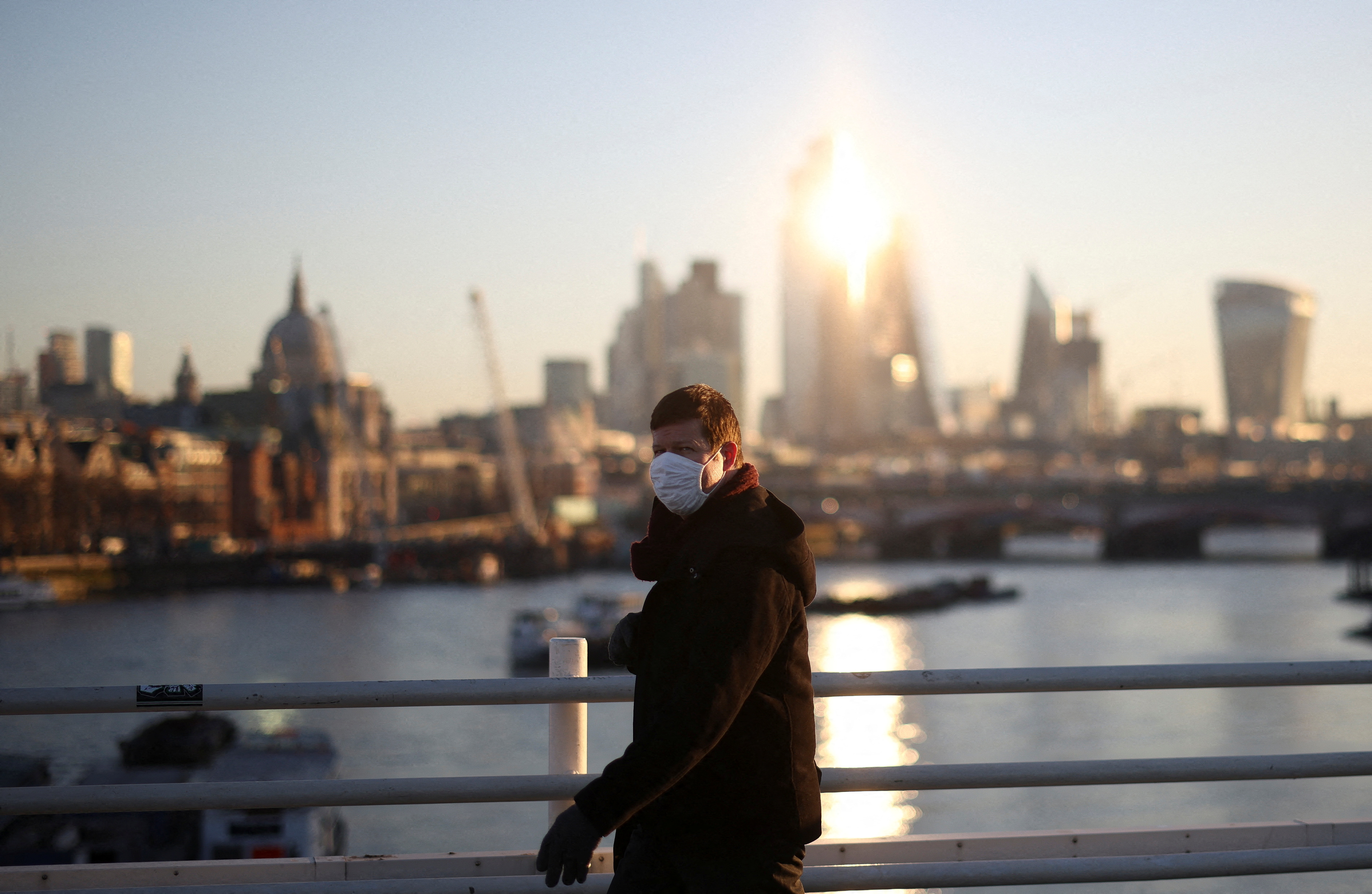 A person wearing a protective face mask walks over Waterloo Bridge during morning rush hour, amid the ongoing coronavirus disease (COVID-19) pandemic in London