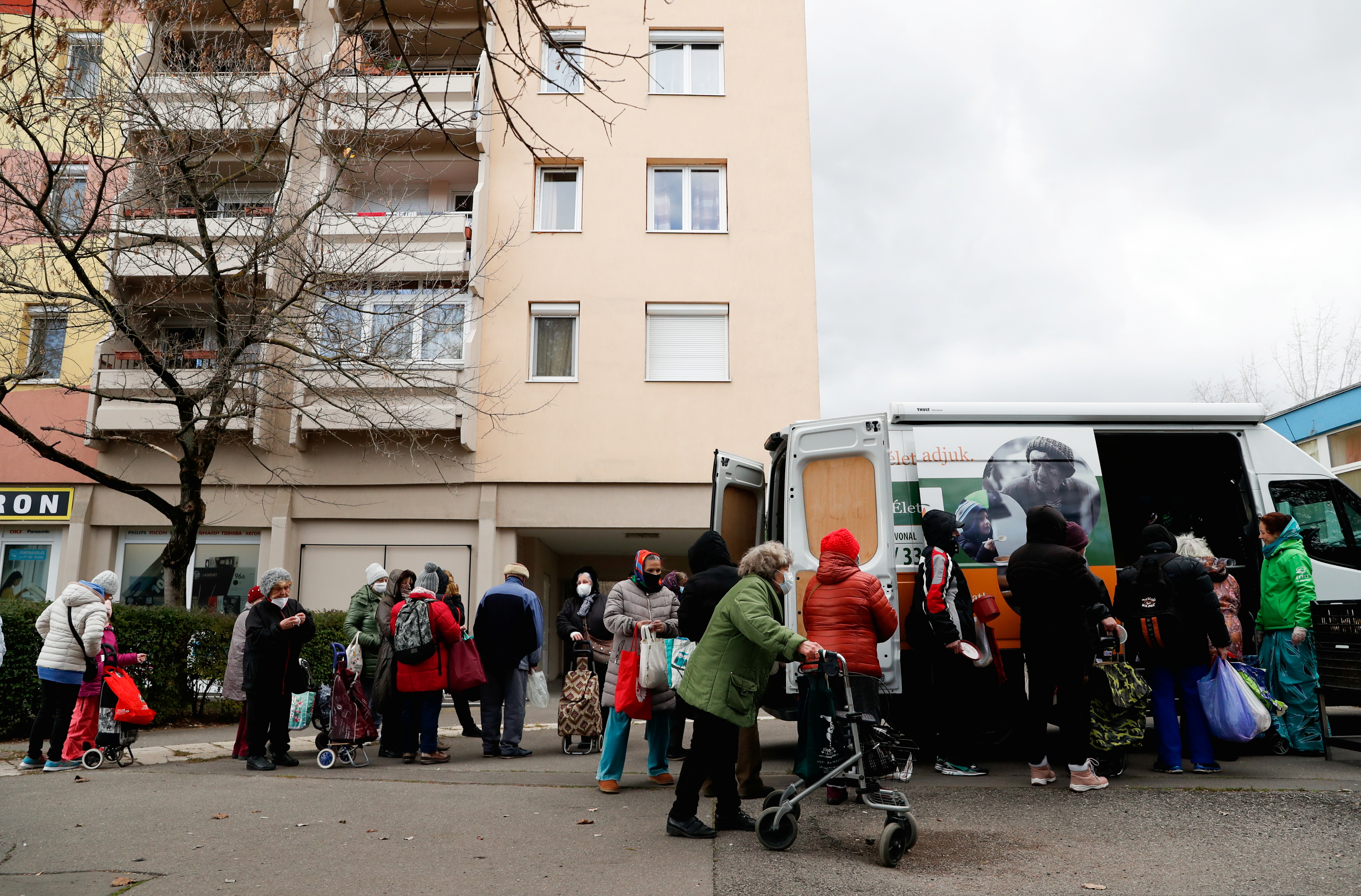 Residents wait in a line for free food from Food for Life Foundation in Budapest