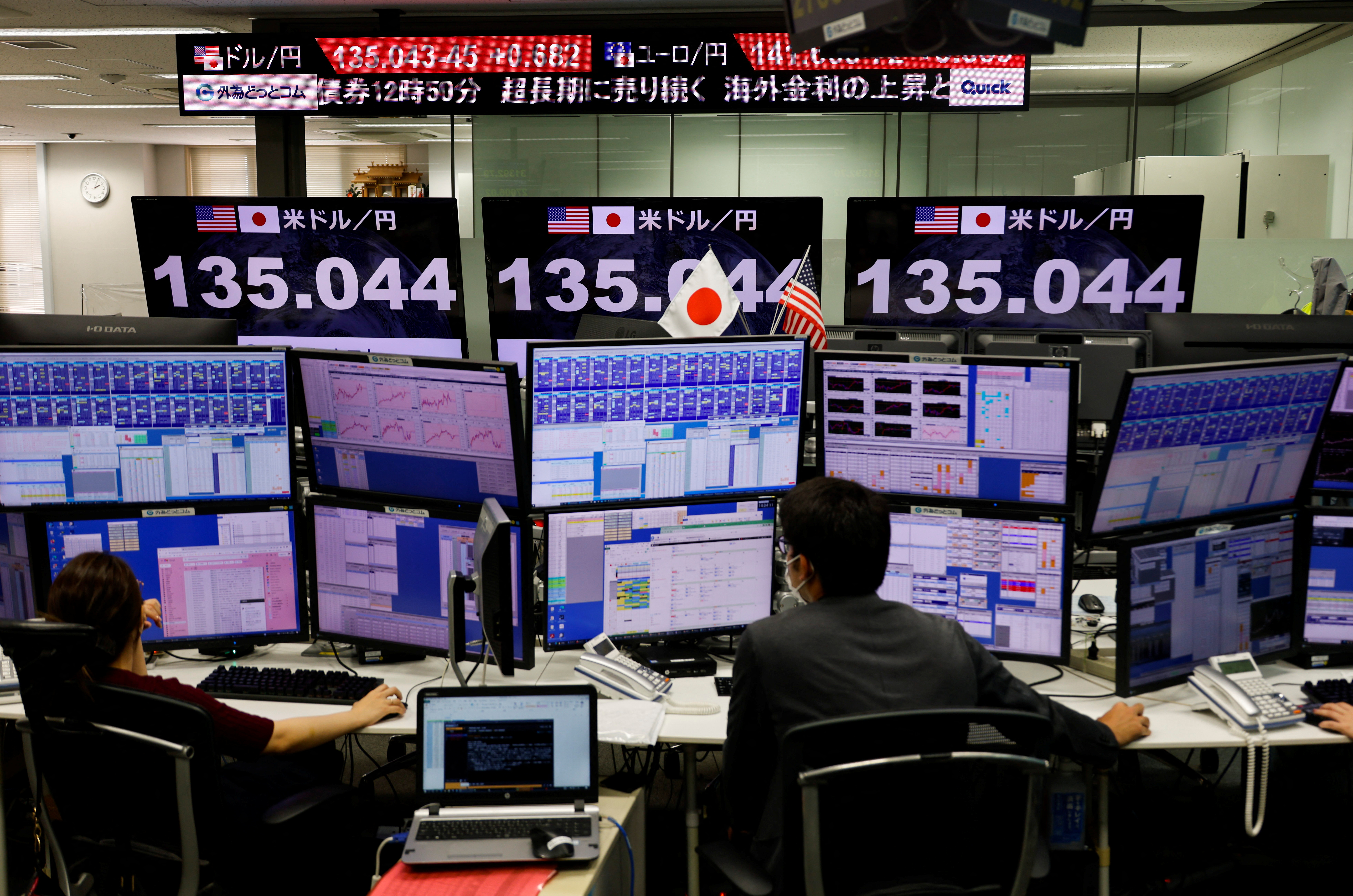 Employees work in front of a monitor showing the Japanese yen exchange rate against the U.S. dollar in Tokyo