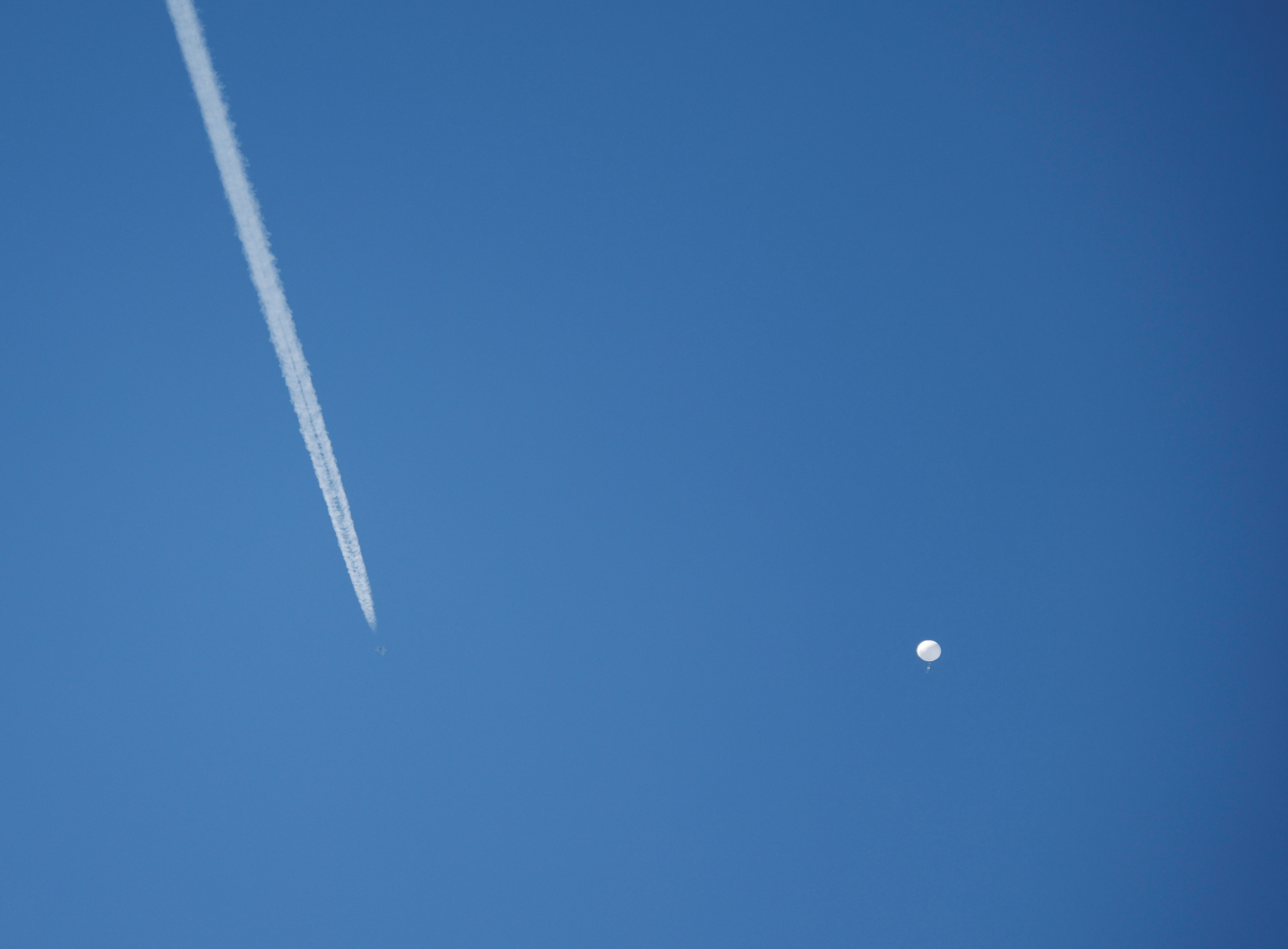 A jet flies by a suspected Chinese spy balloon as it floats off the coast in Surfside Beach