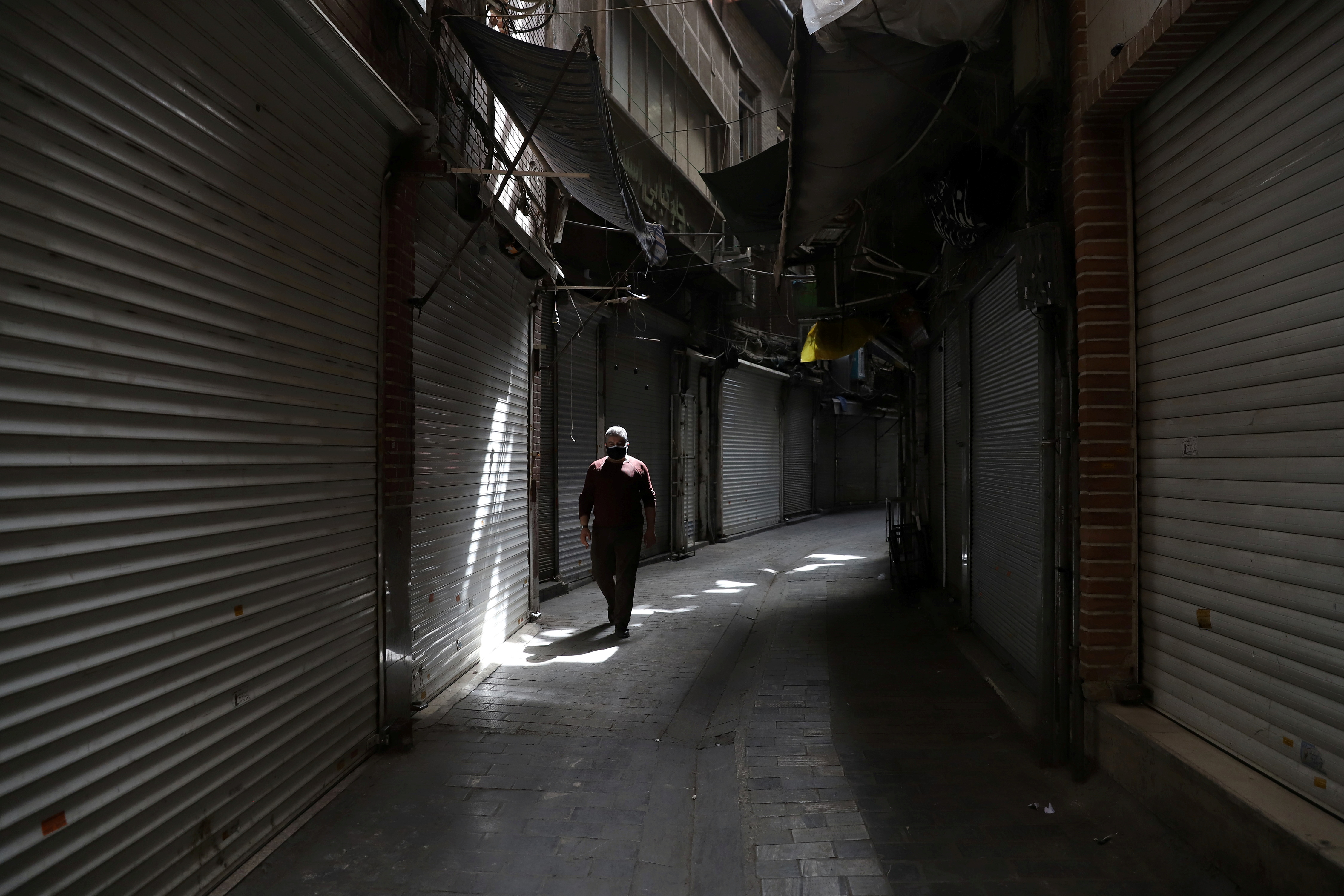 A man walks next to closed shops of Tehran Bazaar following the tightening of restrictions to curb the surge of COVID-19 cases, Tehran, Iran April 10, 2021.