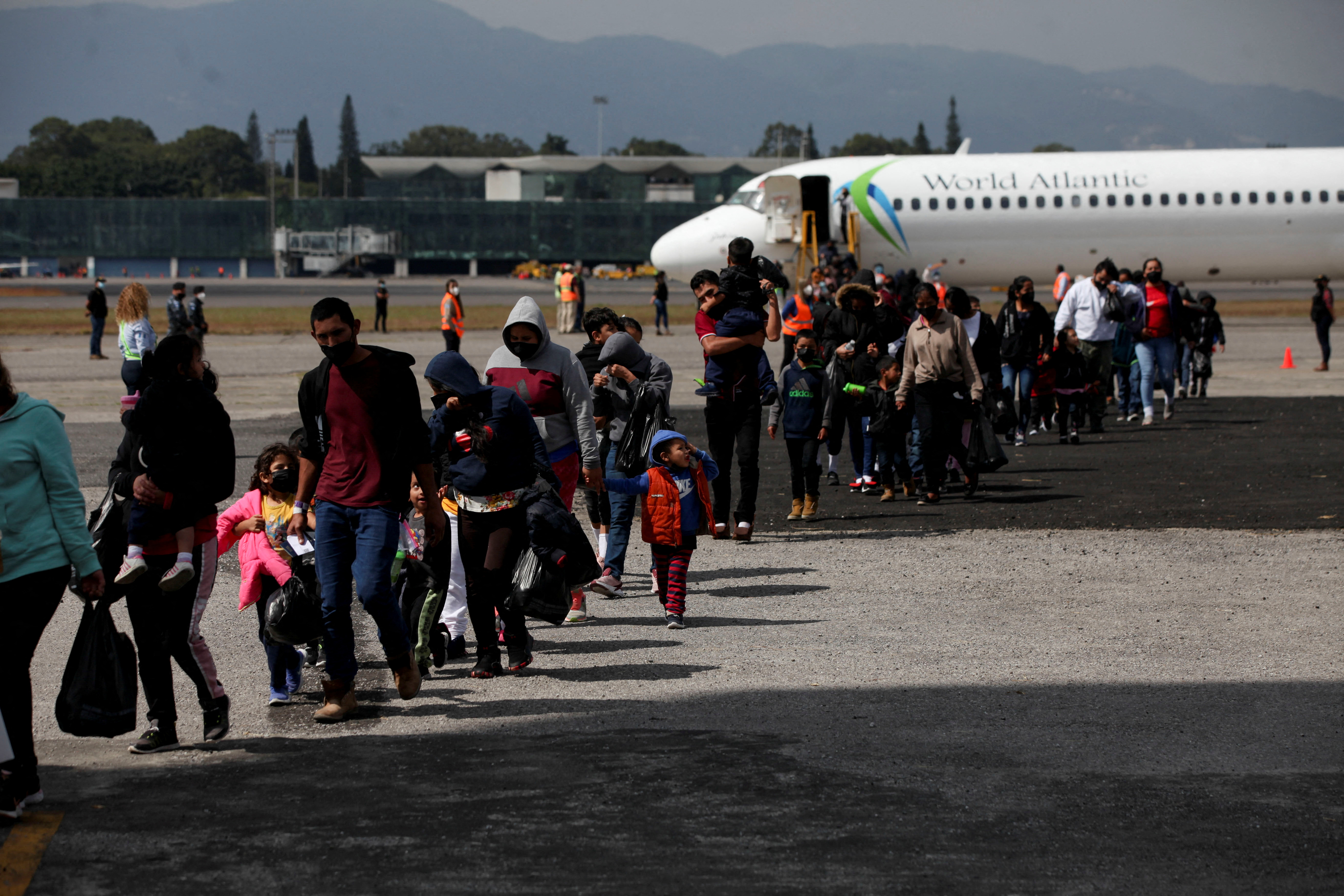 Guatemalan deportees cross the tarmac after arriving on a deportation flight from the U.S., at the Guatemalan Air Force (FAG) headquarters in La Aurora International airport, in Guatemala City, Guatemala December 28, 2021. REUTERS/Sandra Sebastian