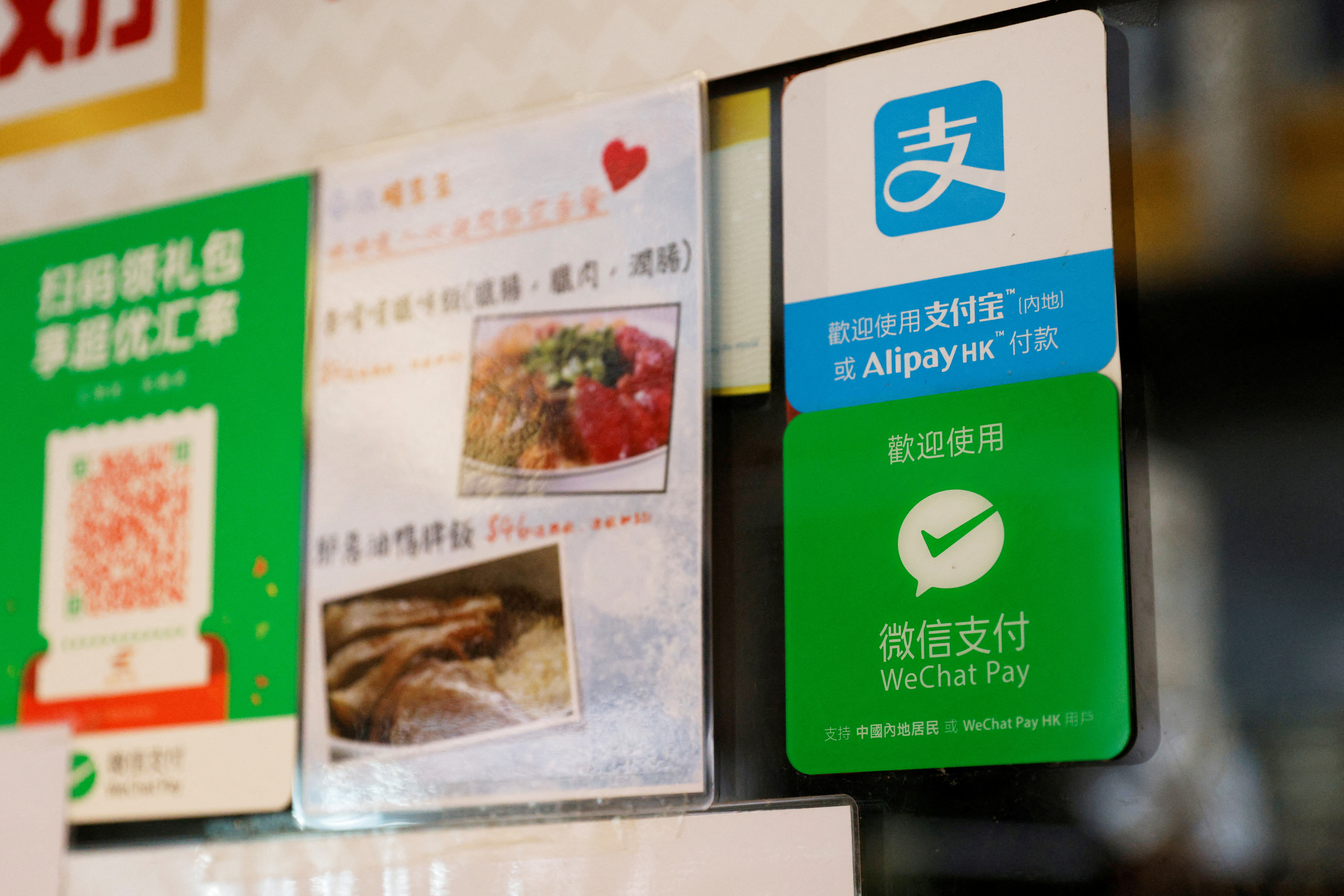 Logos for digital payment services Alipay by Ant Group, an affiliate of Alibaba Group Holding and WeChat Pay by Tencent Holdings are displayed outside a restaurant, in Hong Kong