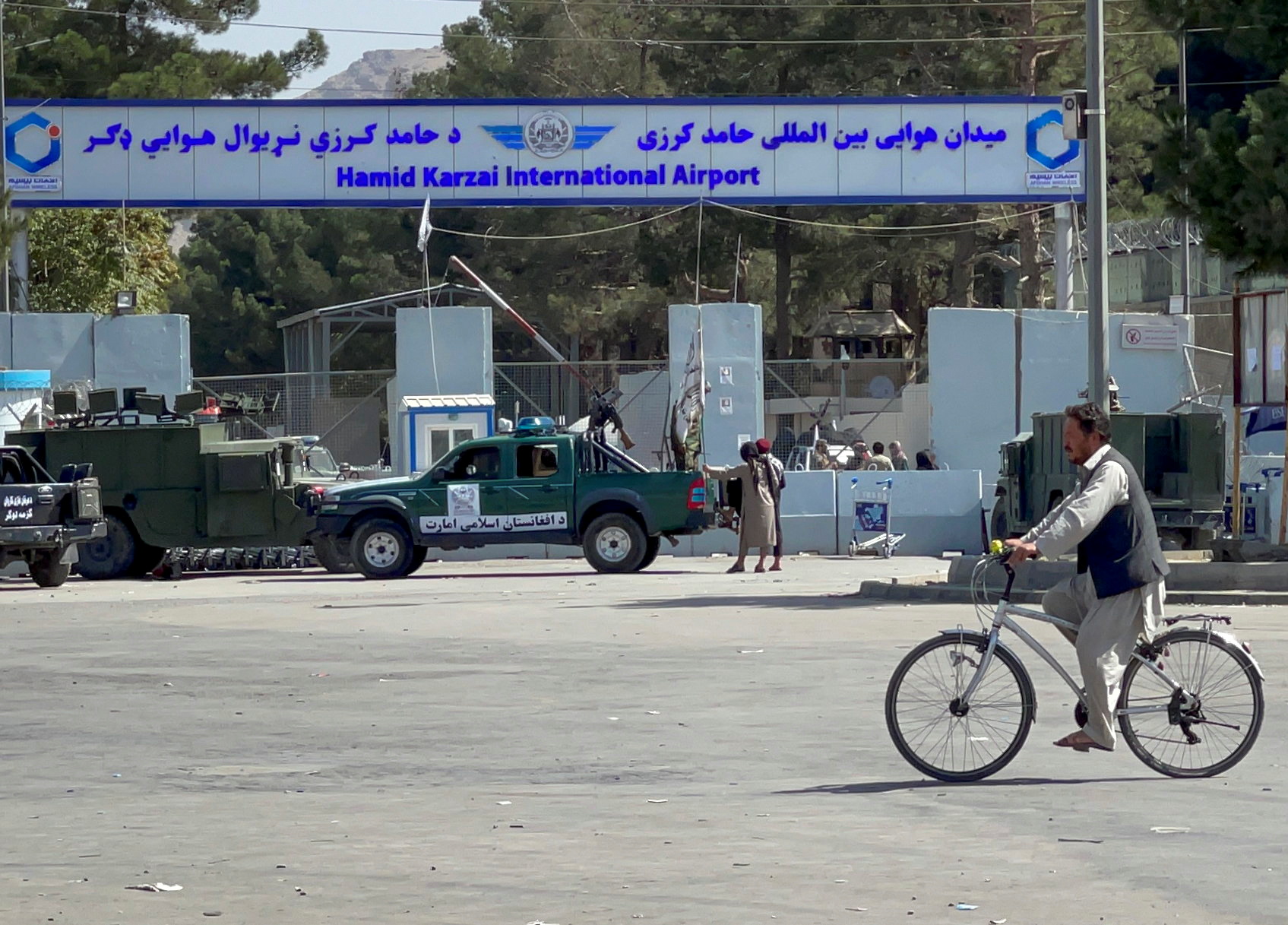 Taliban stand at the entrance gate of Hamid Karzai International airport while Taliban forces block the roads around the airport after yesterday's explosions in Kabul
