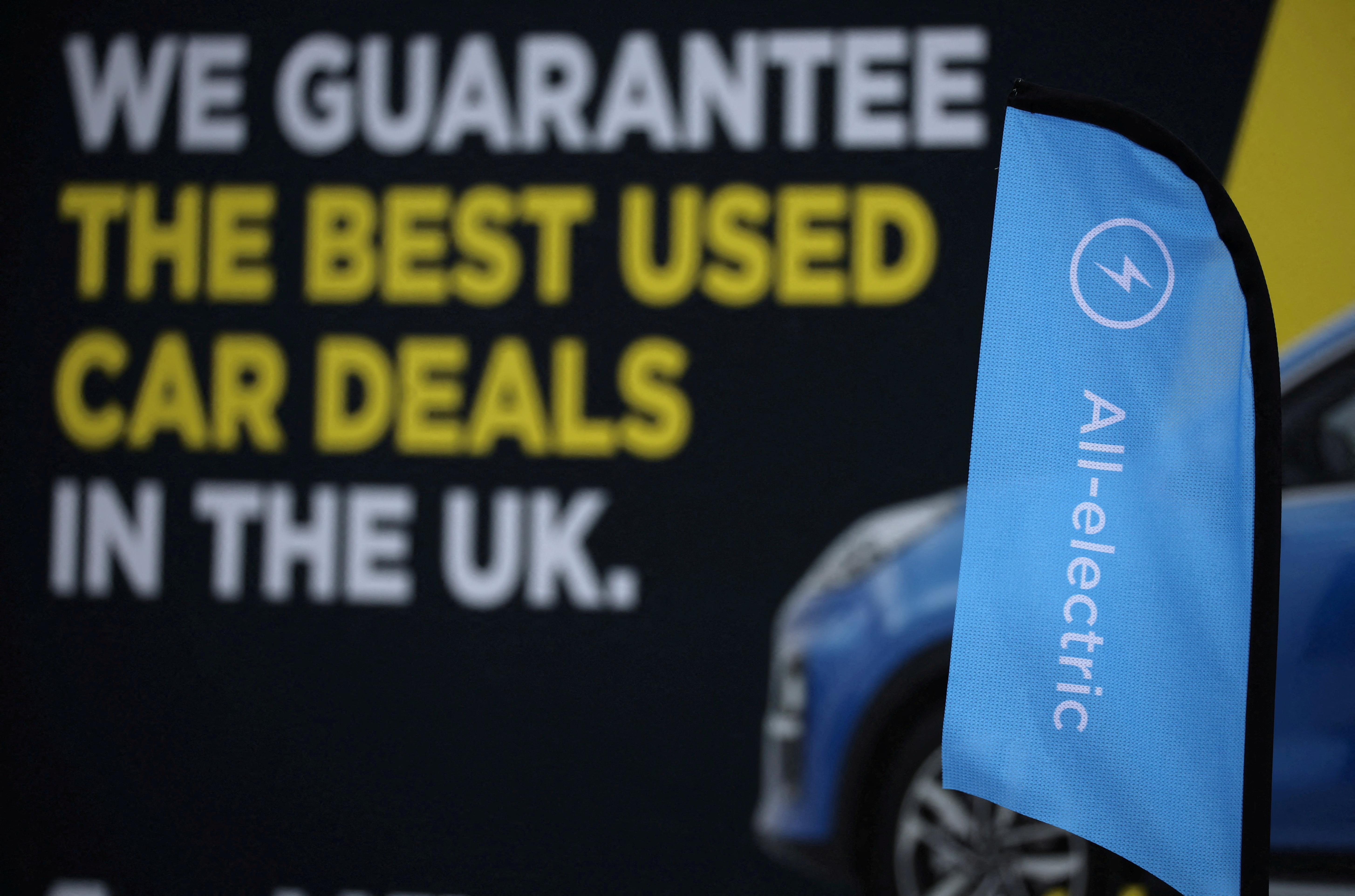 Signage is seen on the forecourt of a used electric vehicle dealer in Manchester