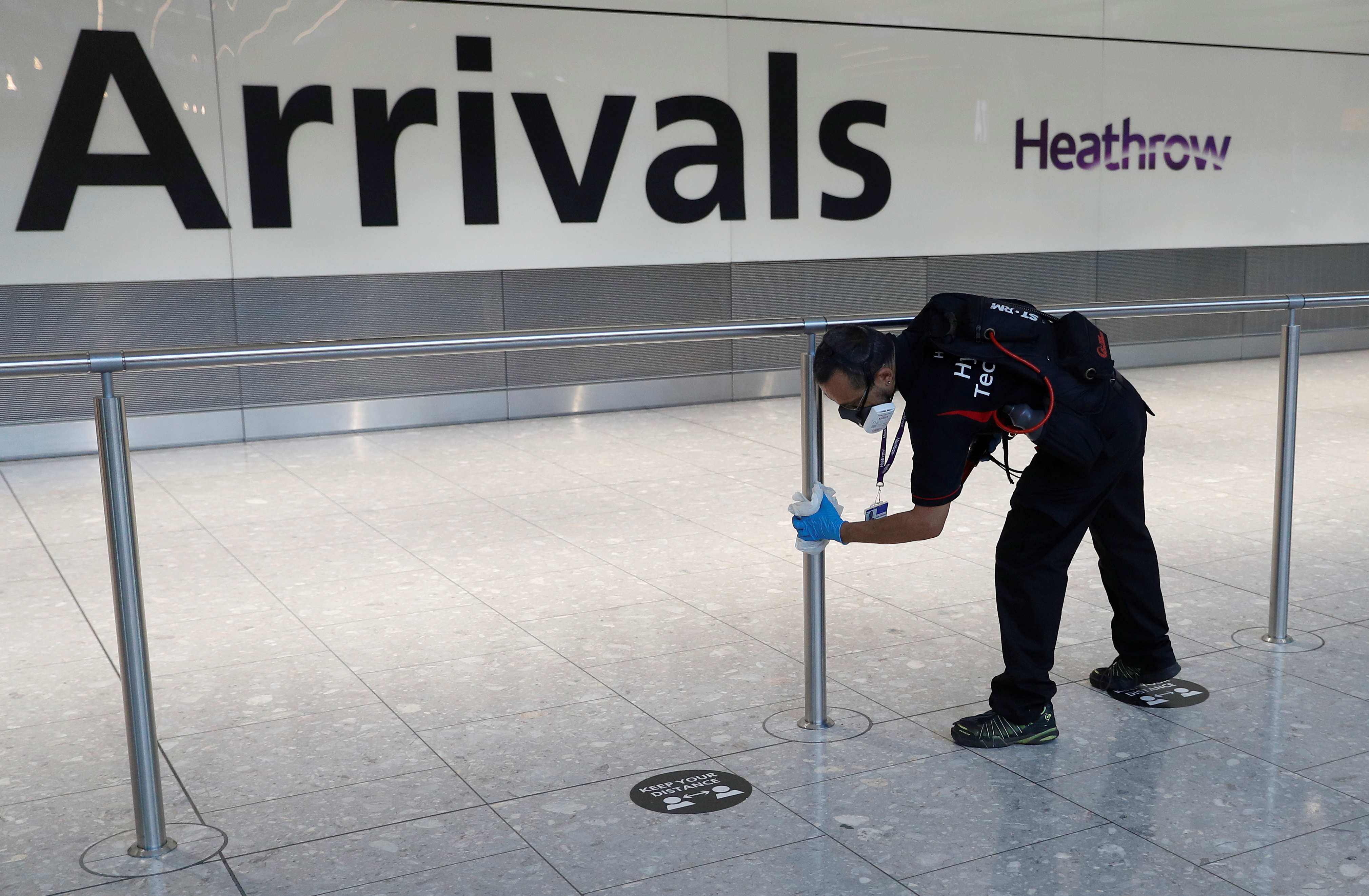 A worker sanitises a barrier at the International arrivals area of Terminal 5 in London's Heathrow Airport, Britain, August 2, 2021.  REUTERS/Peter Nicholls