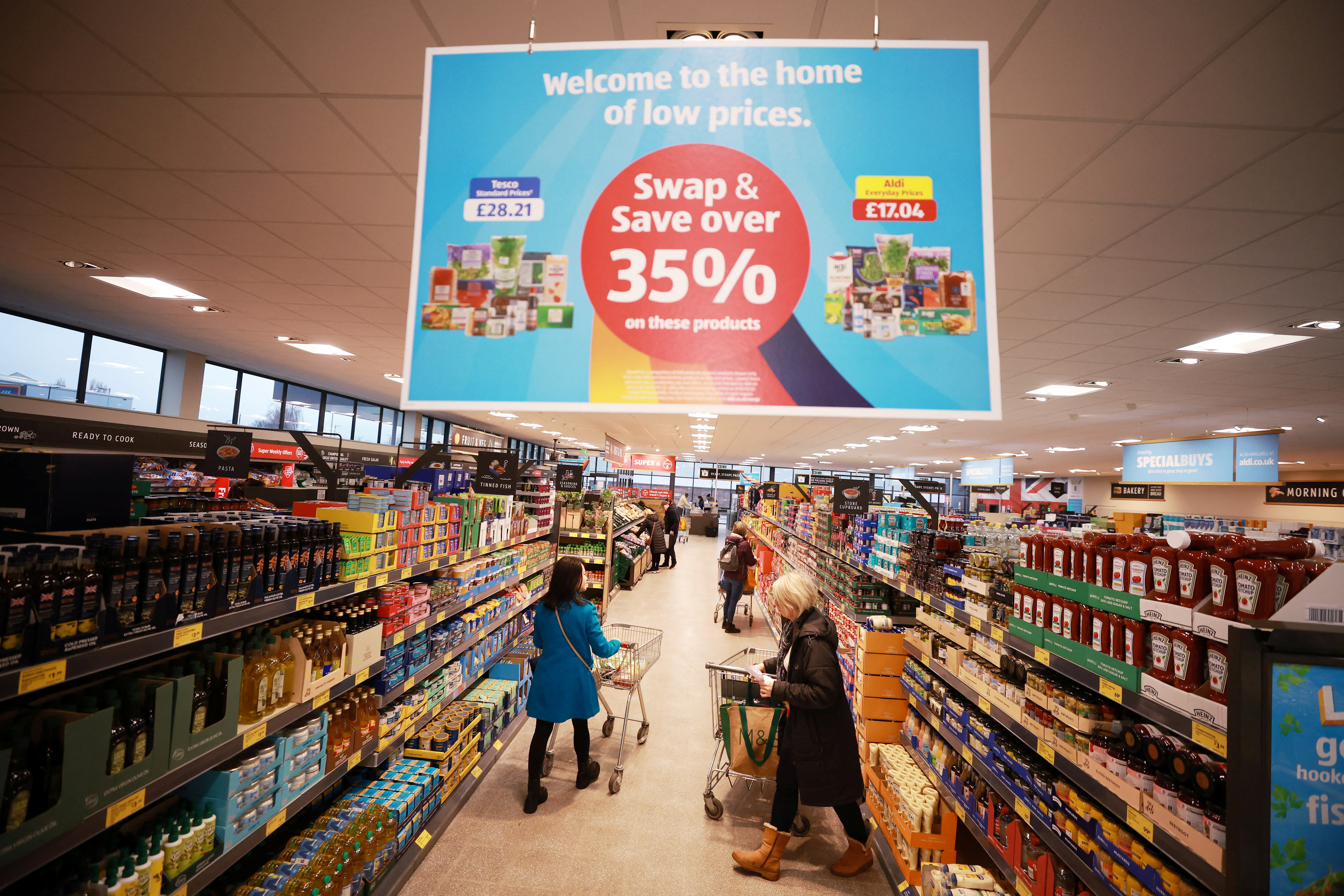 Shoppers push trolleys along an aisle inside an ALDI supermarket near Altrincham