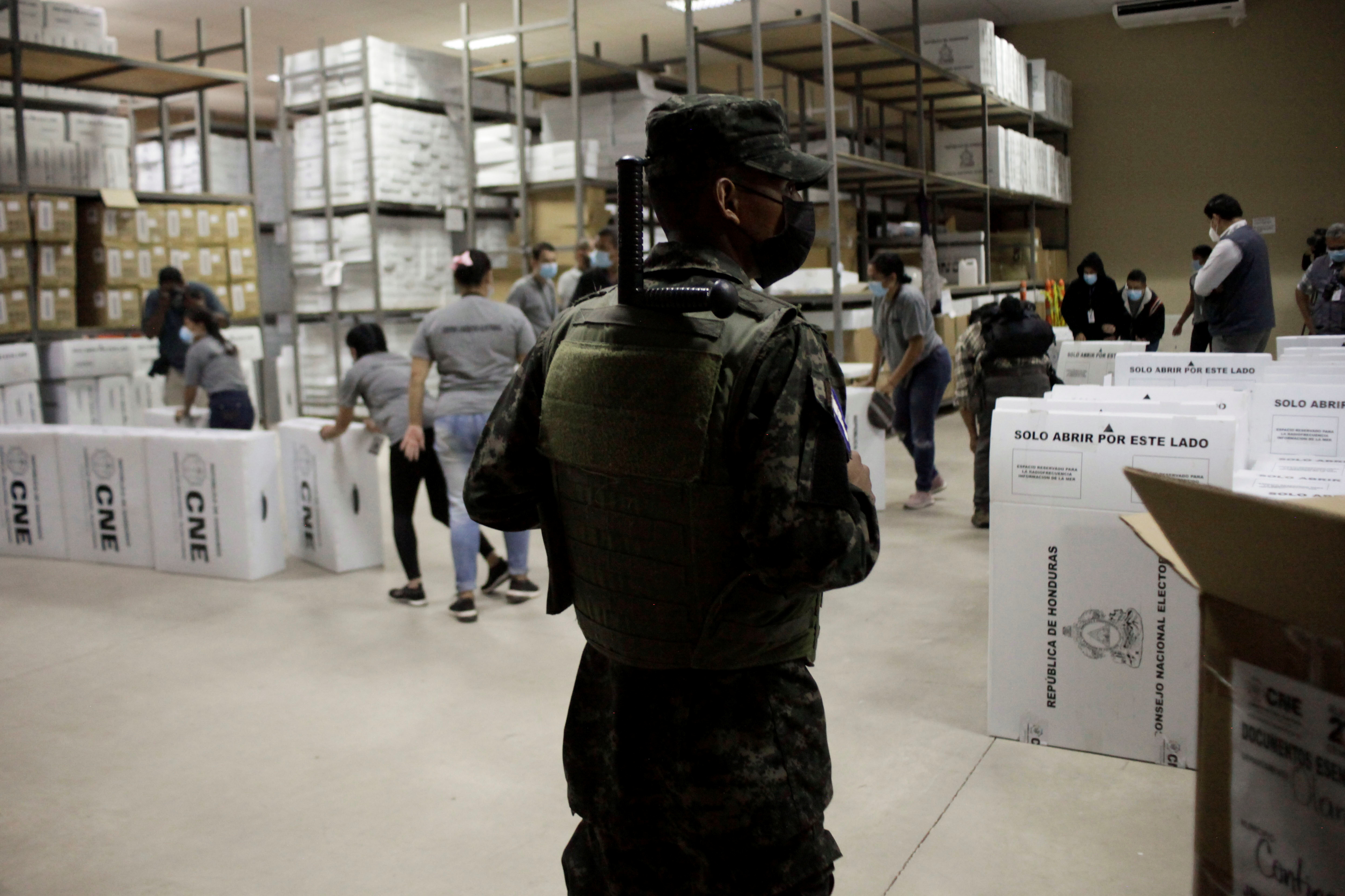 A soldier keeps watch as workers prepare boxes with voting materials for distribution throughout the country ahead of the November 28 general election, in Tegucigalpa, Honduras November 23, 2021. REUTERS/Fredy Rodriguez