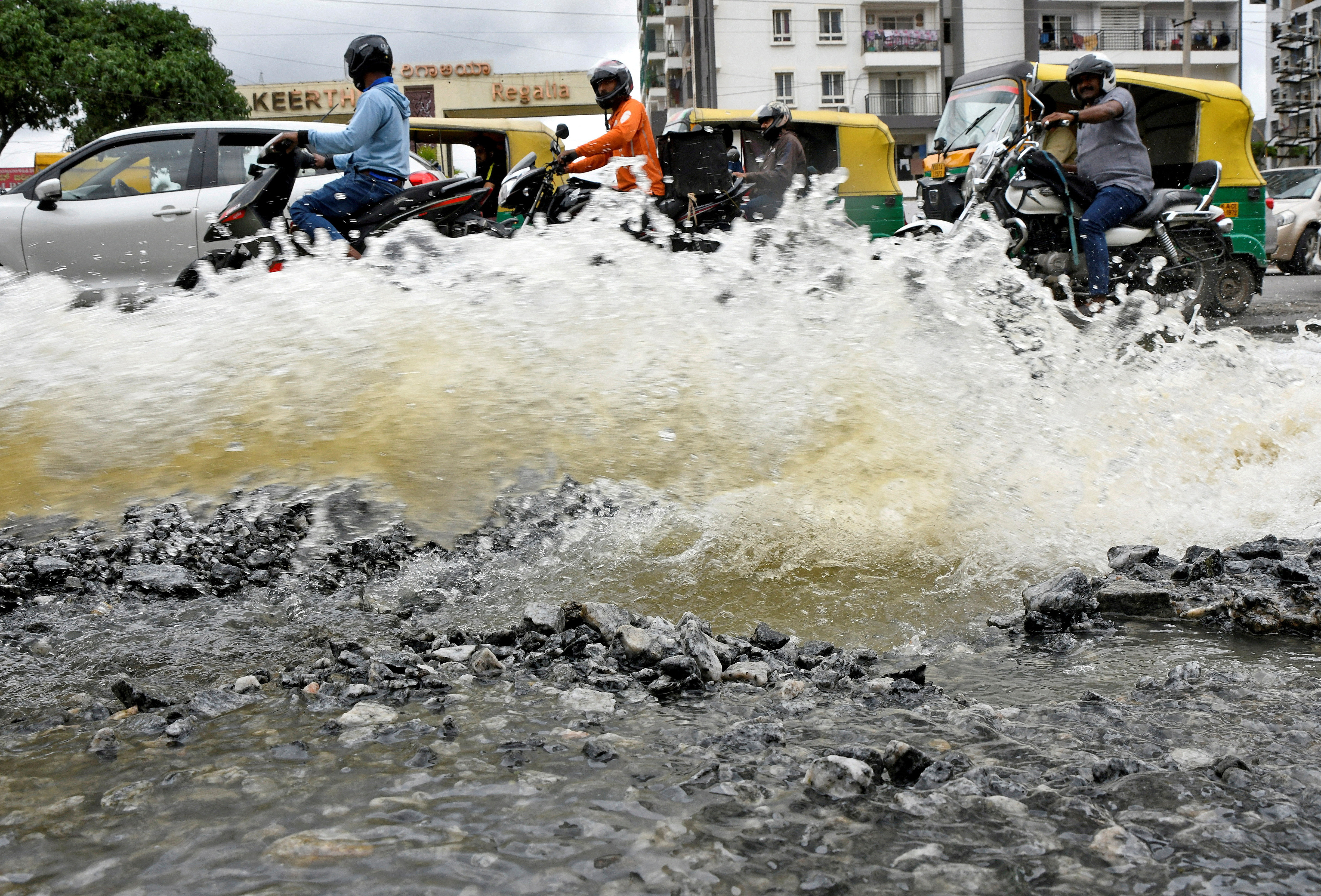 Traffic moves as water is pumped out of an inundated residential area following torrential rains in Bengaluru