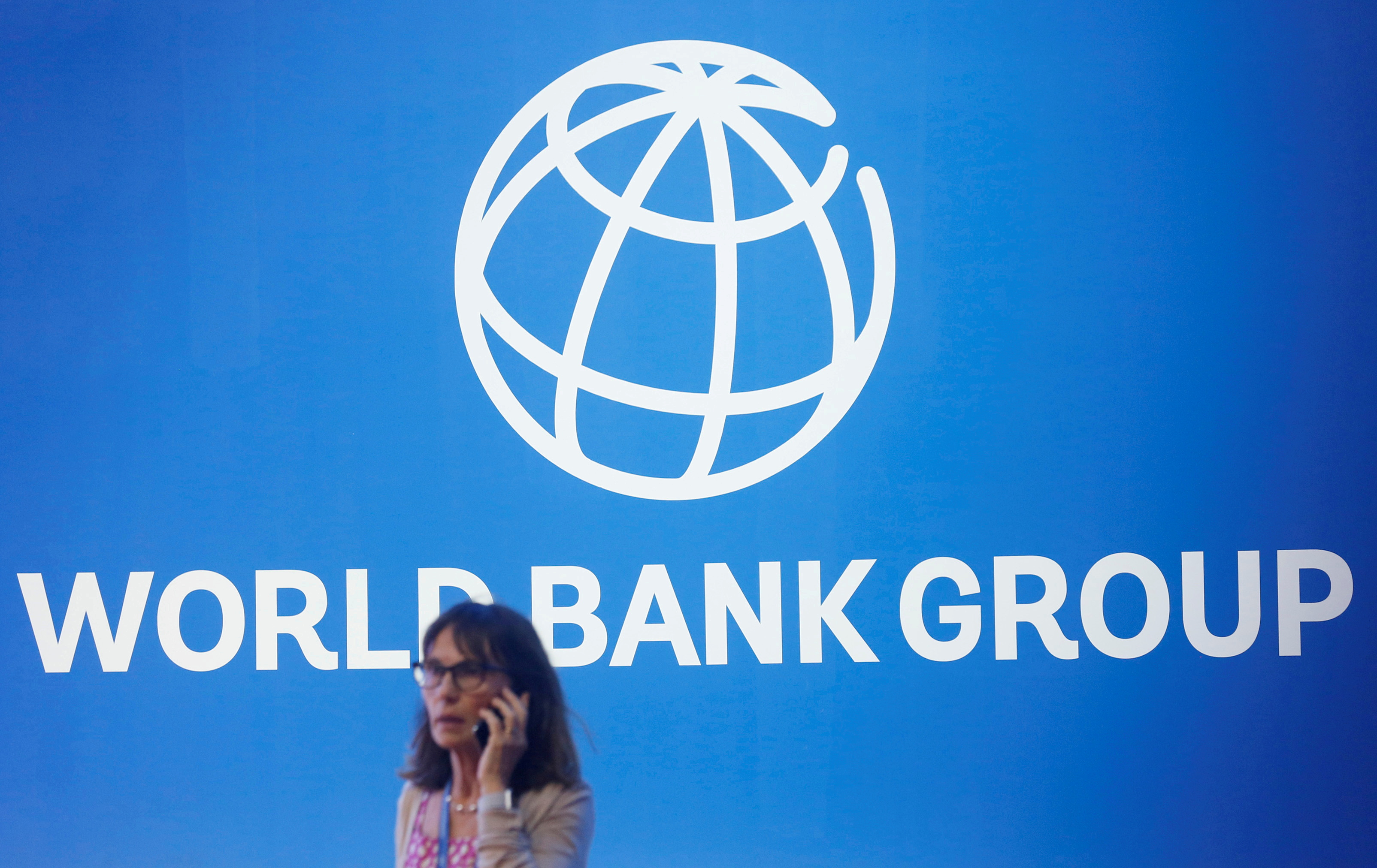 A participant stands near a logo of World Bank at the International Monetary Fund - World Bank Annual Meeting 2018 in Nusa Dua, Bali, Indonesia, October 12, 2018. REUTERS/Johannes P. Christo/File Photo
