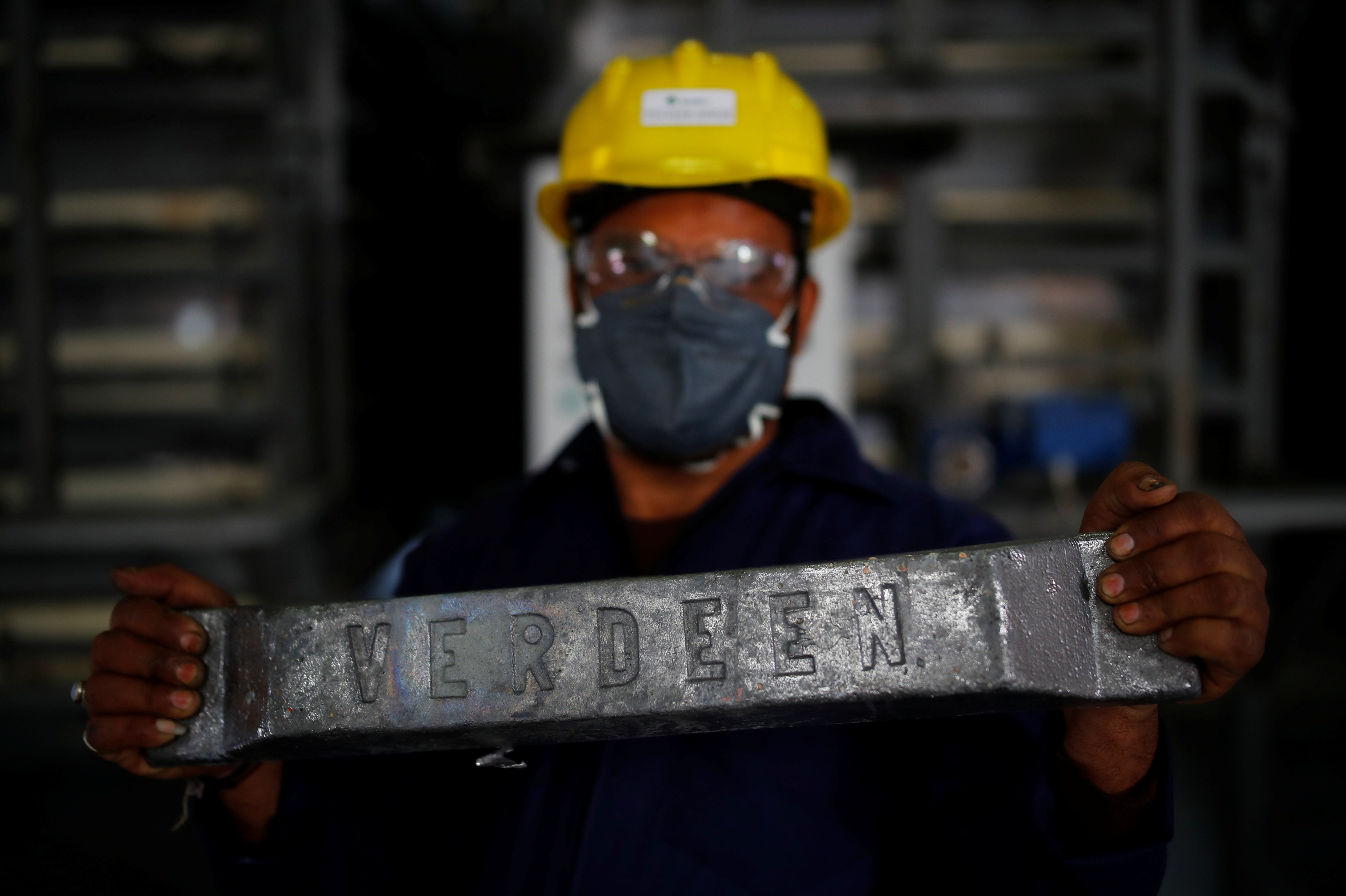 A worker shows an ingot made from lead at ACE Green recycling Inc in Ghaziabad