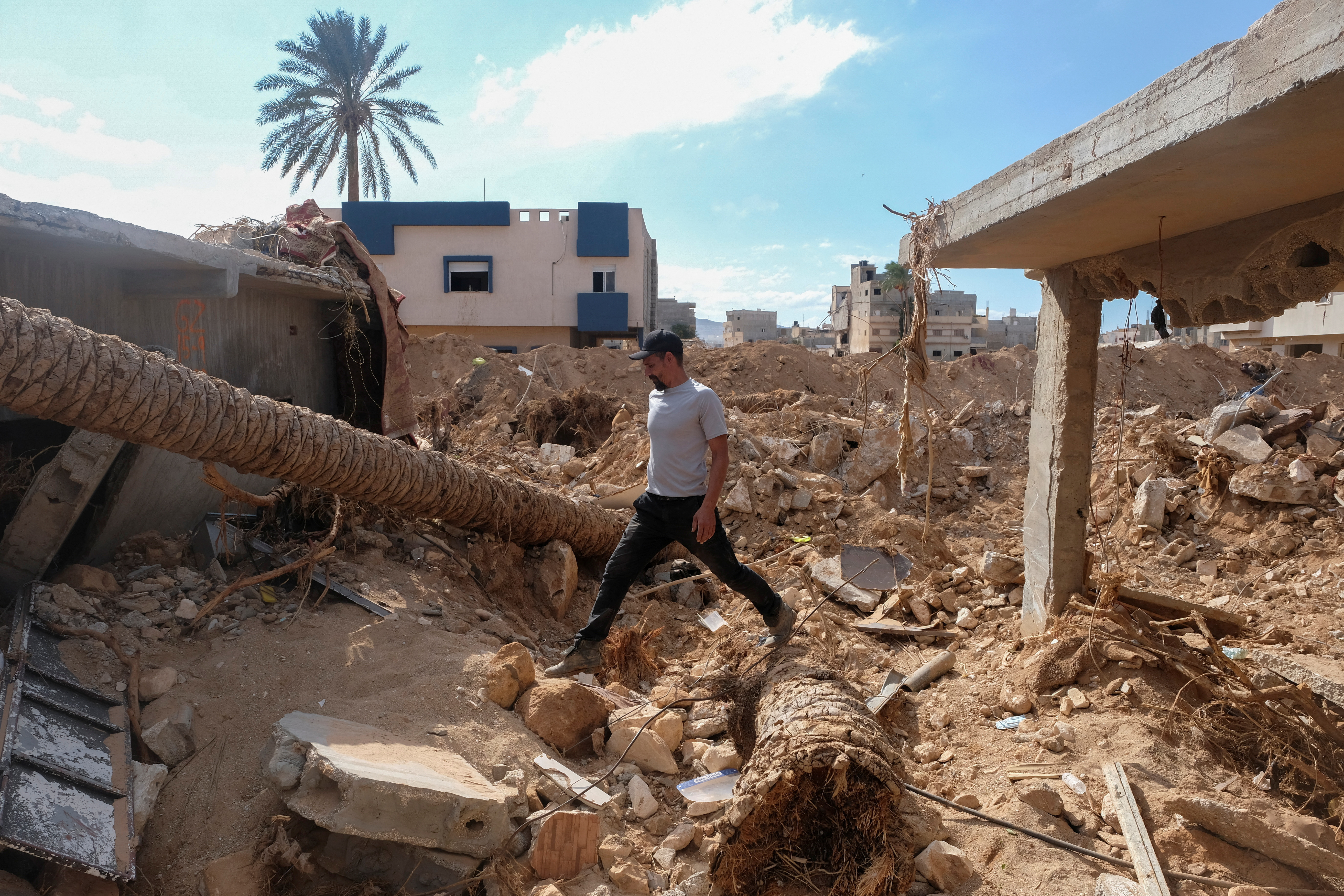 Abdul Salam Ibrahim Al-Qadi, 43 years old, walks on the rubble in front of his house, searching for his missing father and brother after the deadly floods in Derna