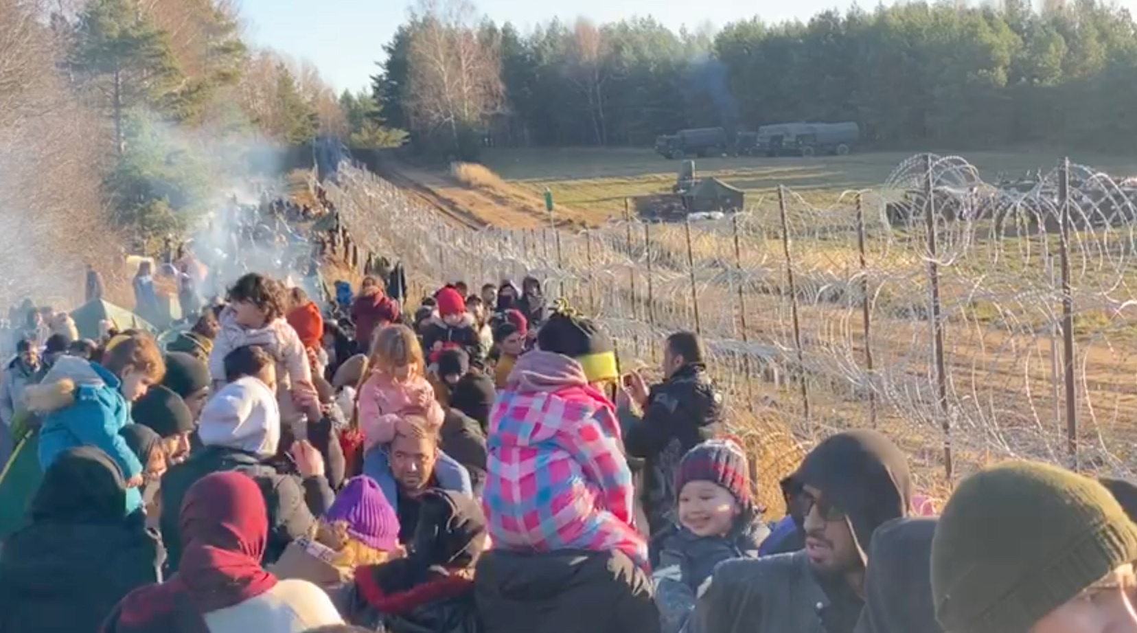 Migrants gather near a barbed wire fence on the Poland - Belarus border