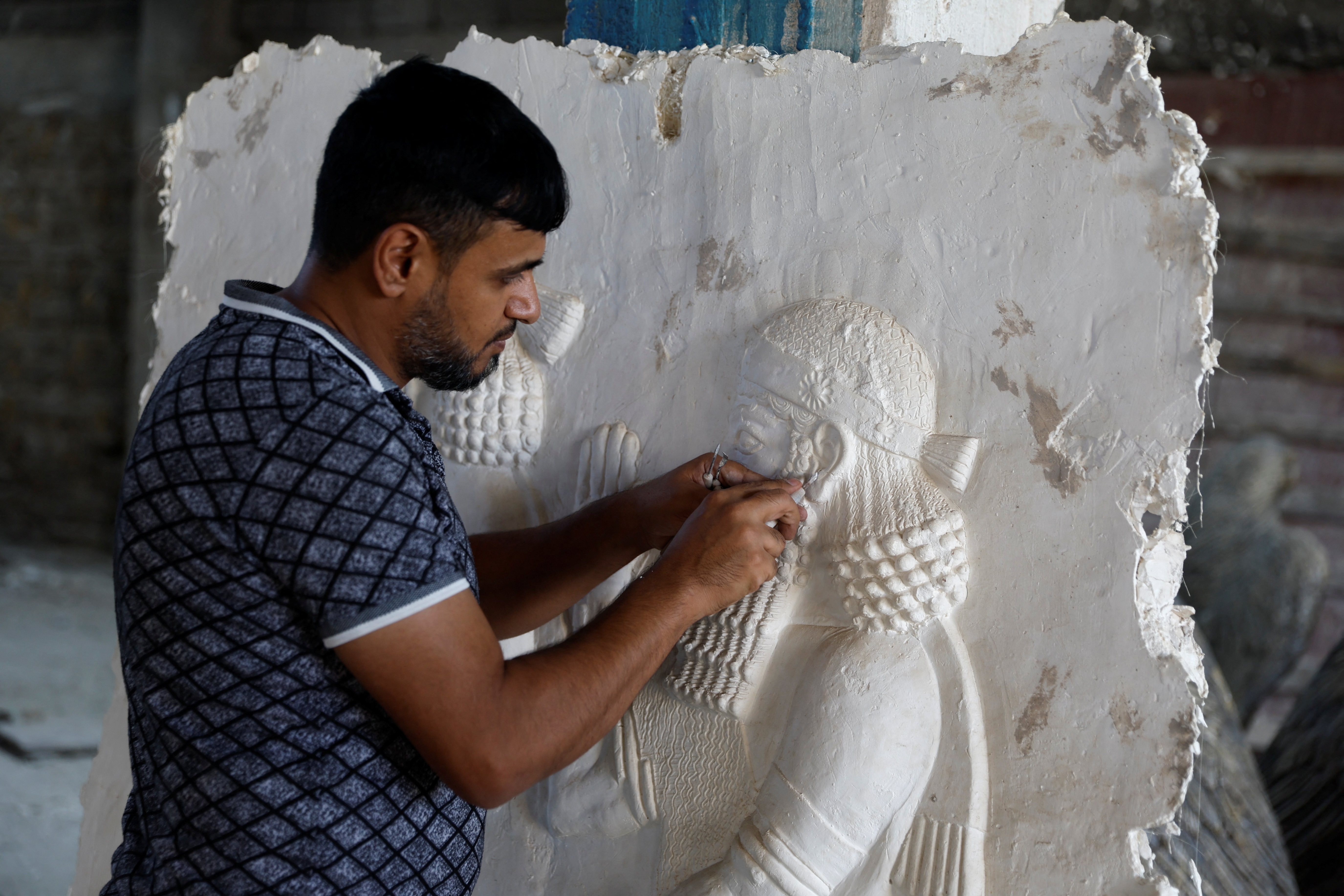 The sculptor Khaled al-Abadi works inside his workshop on his sculptures which depict scenes from the history of the city of Mosul, in Mosul