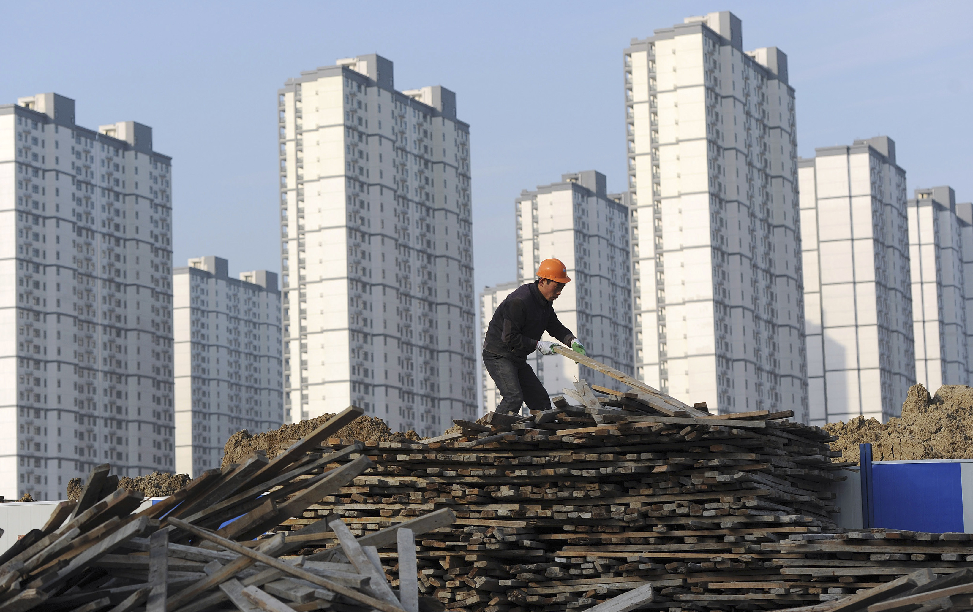 A labourer selects wooden planks as he works at a residential construction site in Hefei