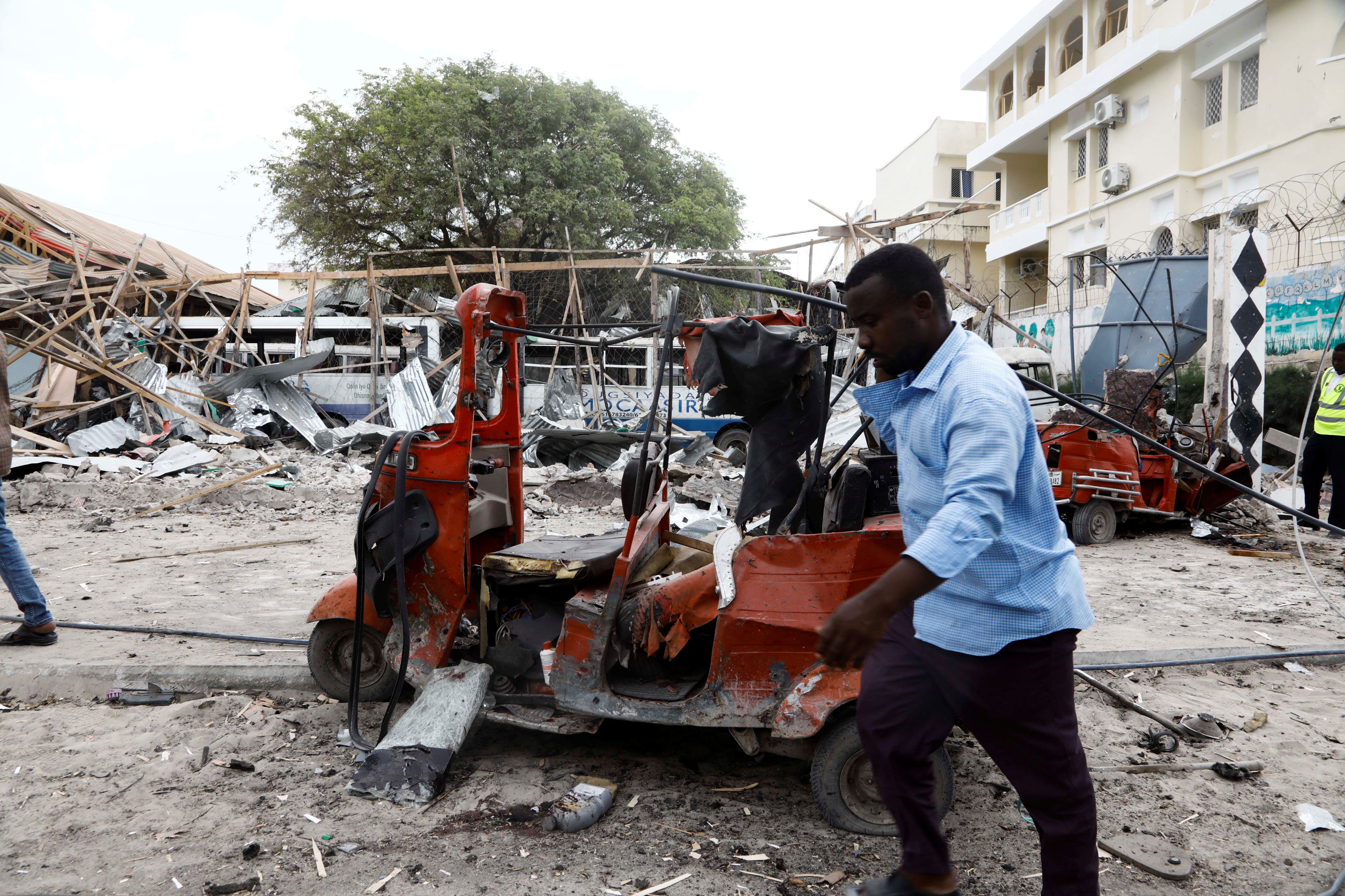 A civilian walks past the wreckages of vehicles and the debris of classrooms after a car exploded in a suicide attack near Mucassar primary and secondary school in Hodan district of Mogadishu