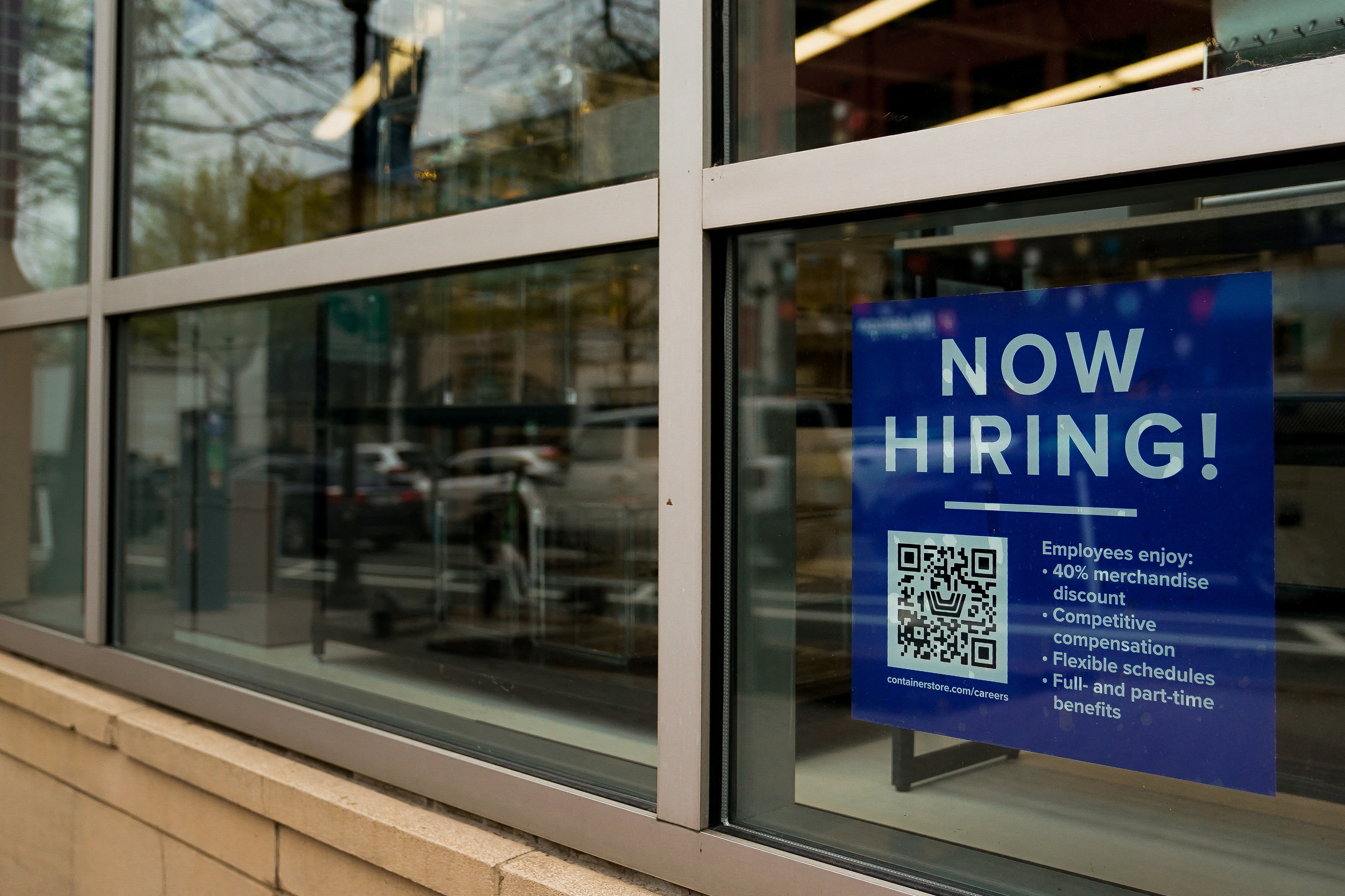 An employee hiring sign with a QR code in the window of a business in Arlington