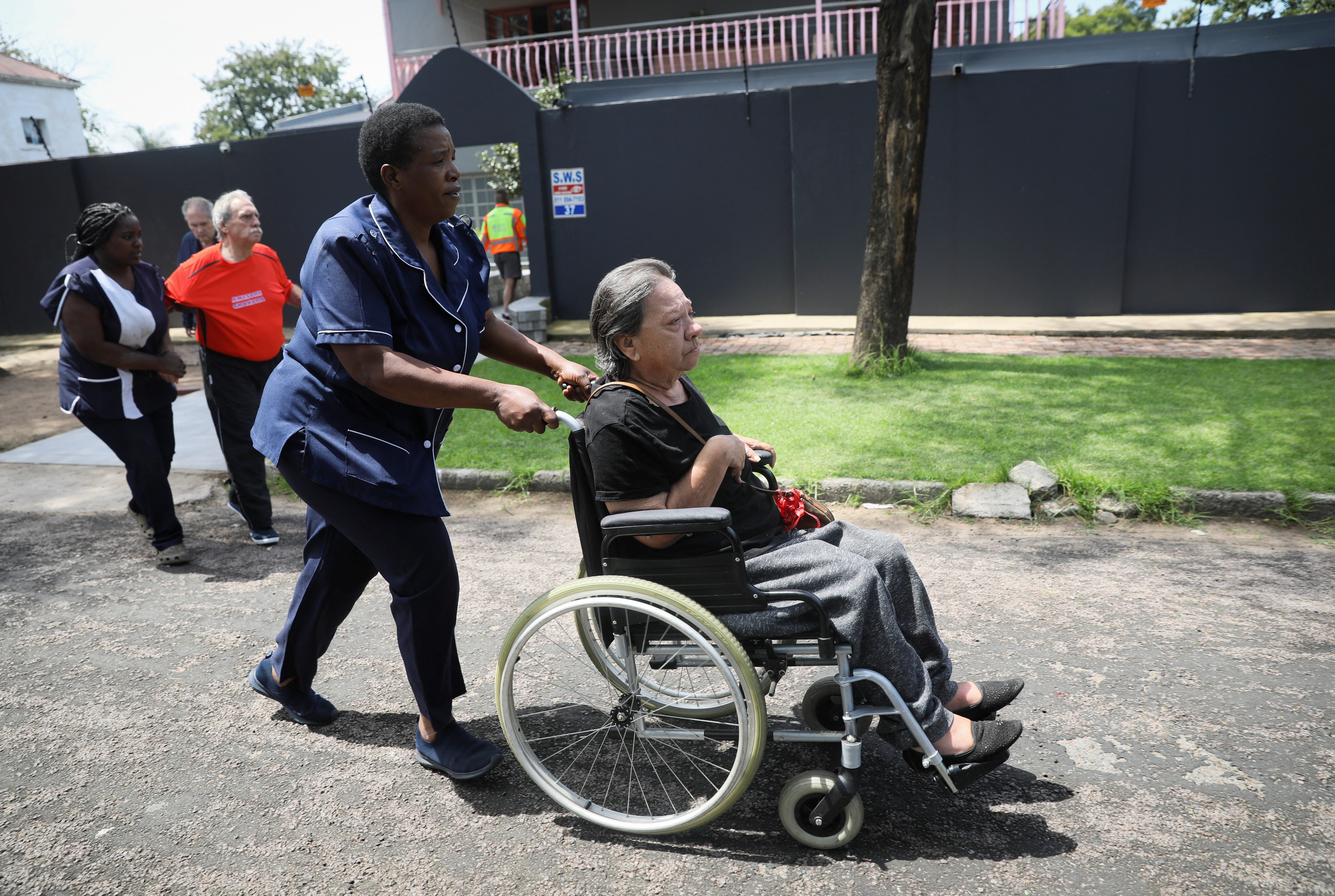 Healthcare workers evacuate patients from an elderly care facility near the scene where a gas tanker exploded in Boksburg near Johannesburg