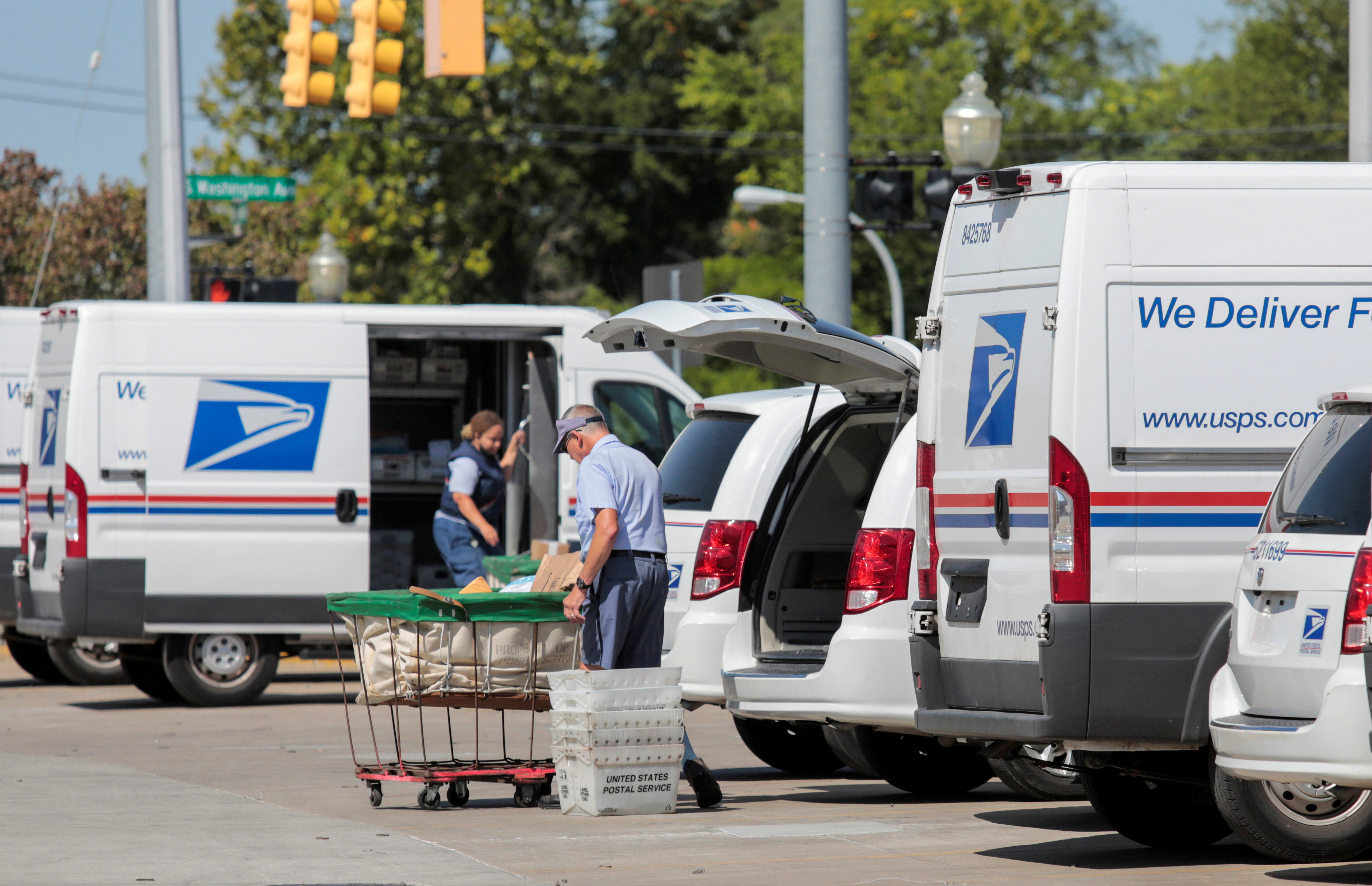 United States Postal Service workers load mail into delivery trucks outside a post office in Royal Oak