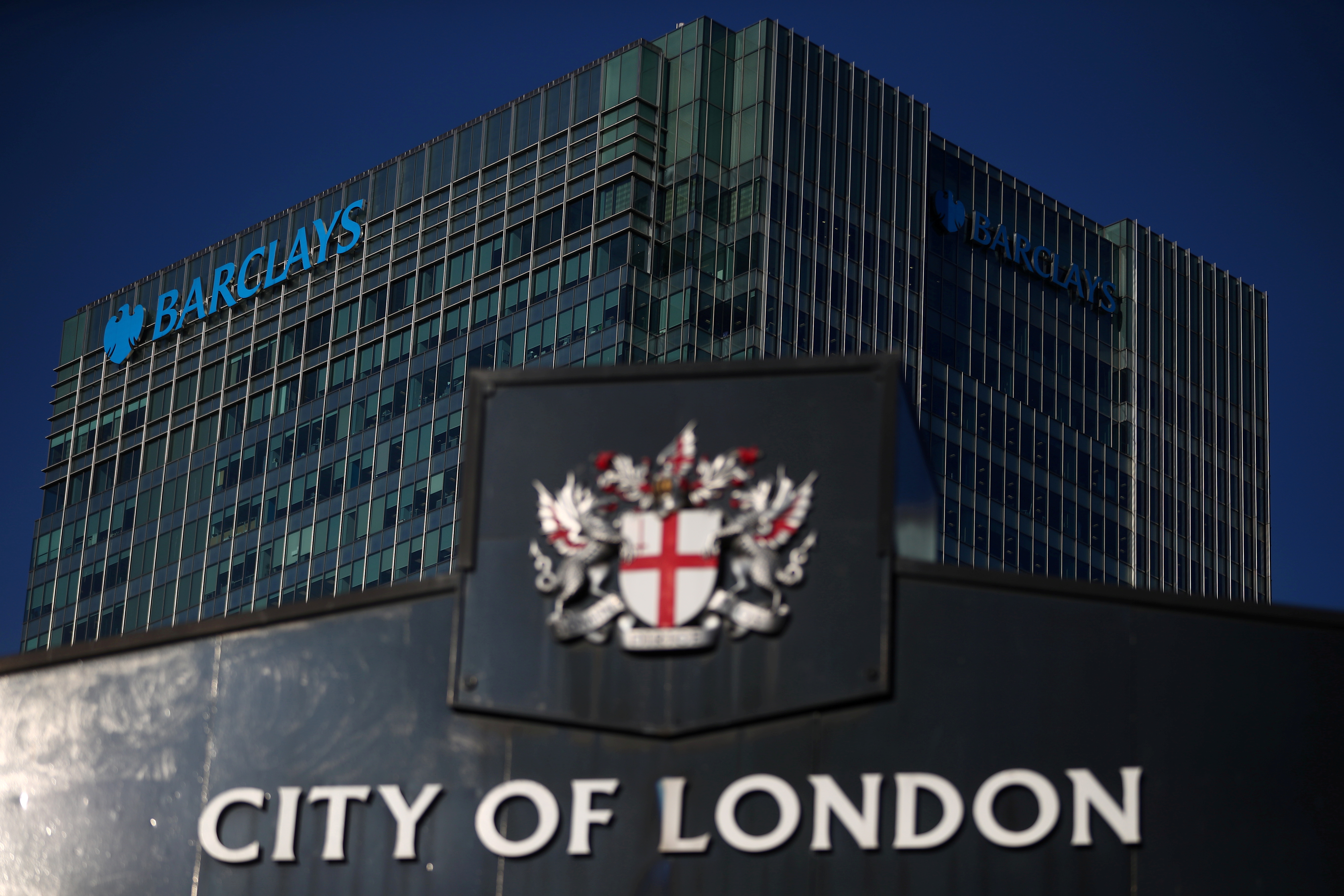 Barclays' building in Canary Wharf is seen behind a City of London sign outside Billingsgate Market in London, Britain, August 8, 2018. REUTERS/Hannah McKay/File Photo  