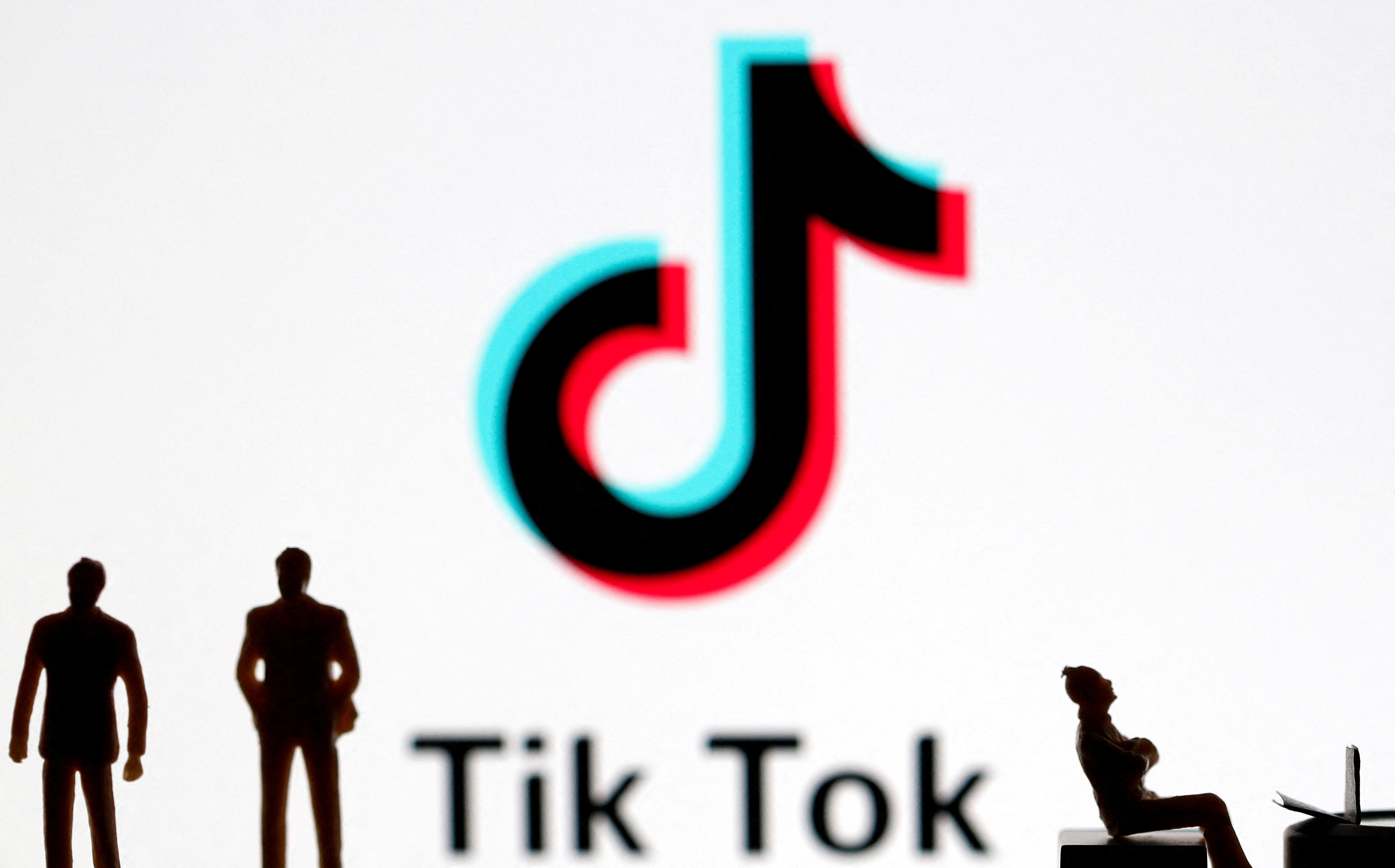 A 3-D printed figures are seen in front of displayed Tik Tok logo in this picture illustration
