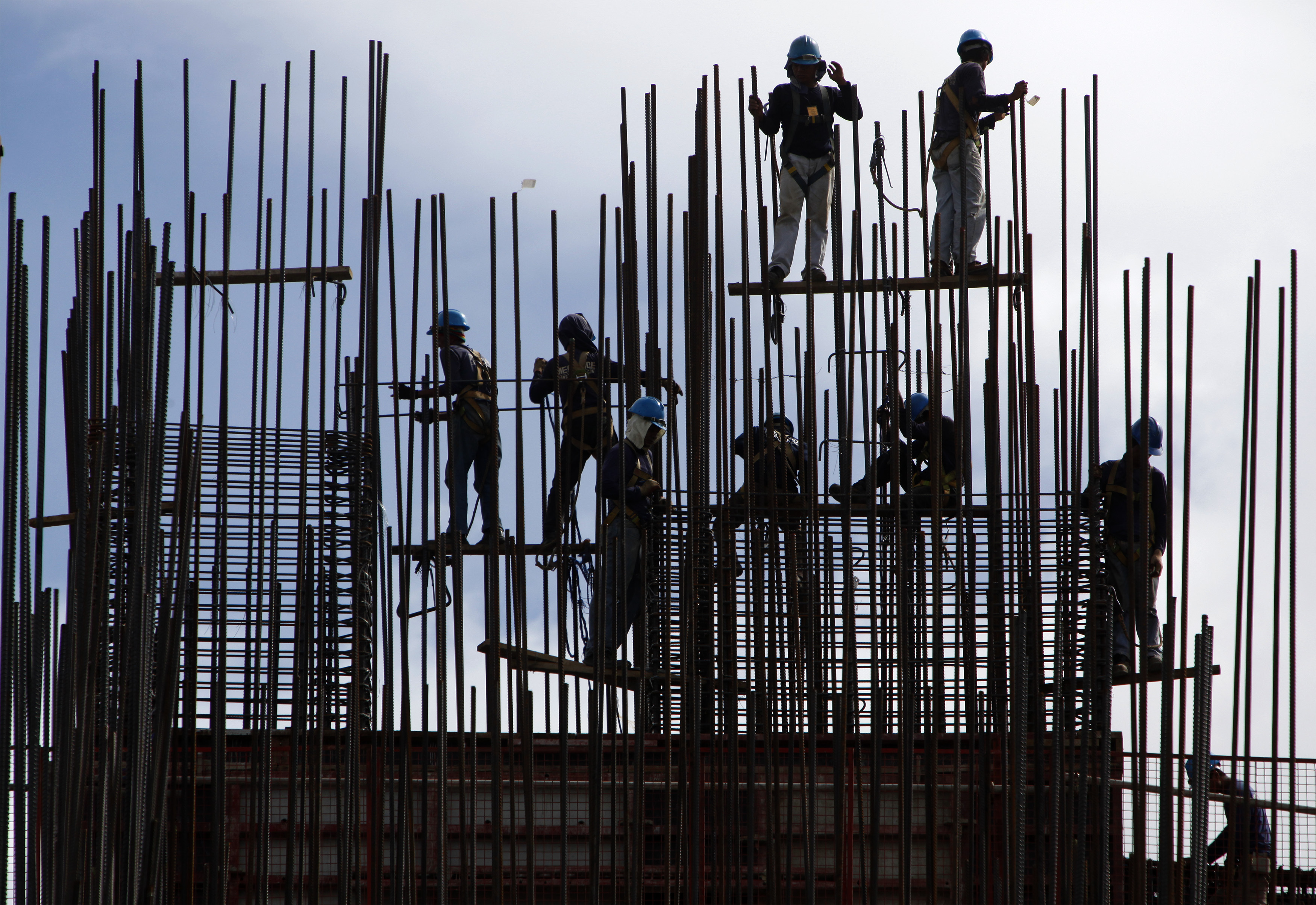 Construction workers prepare steel bars before cement is poured at a building project