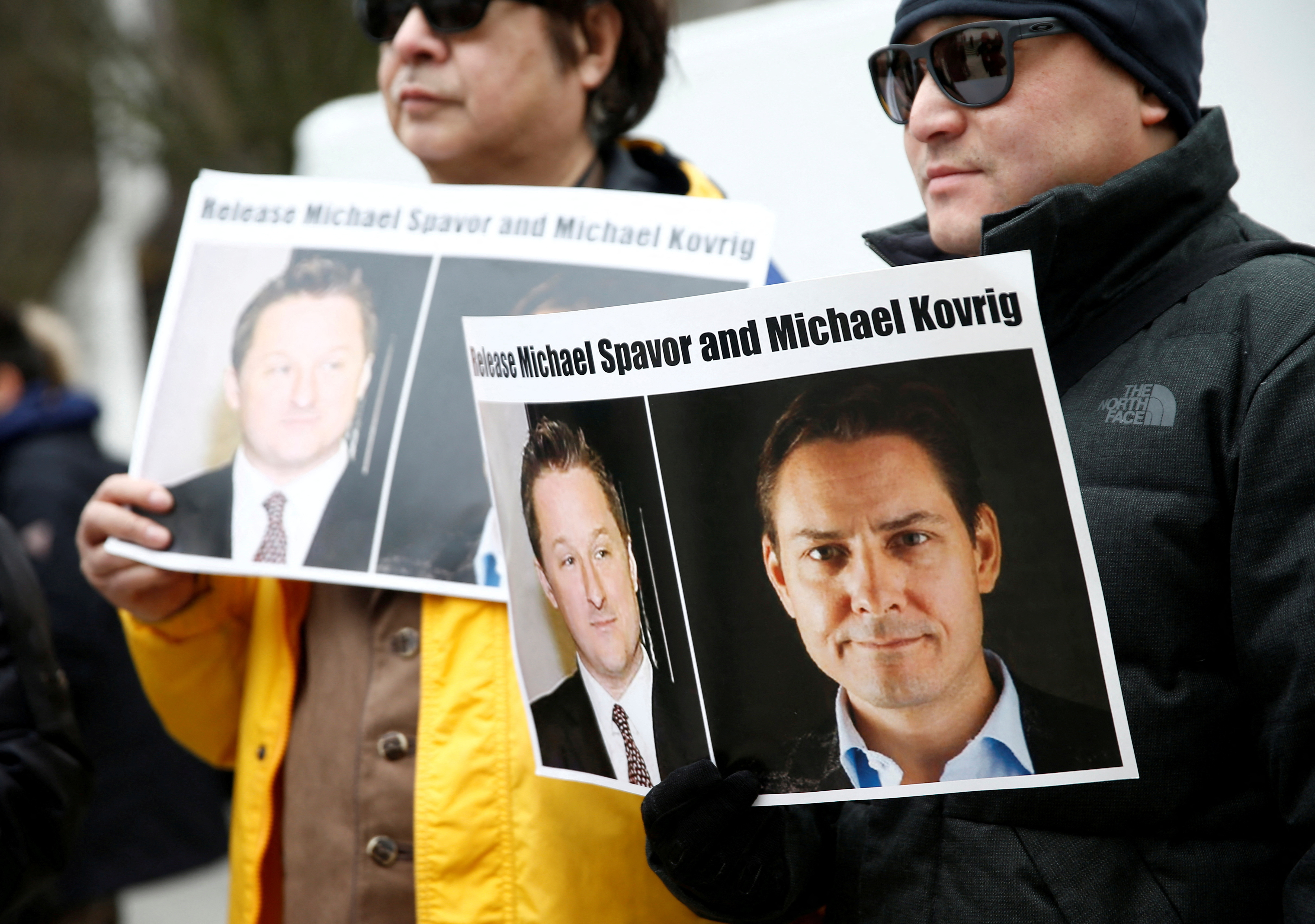 People hold signs calling for China to release Canadian detainees Spavor and Kovrig during an extradition hearing for Huawei Technologies Chief Financial Officer Meng Wanzhou at the B.C. Supreme Court in Vancouver