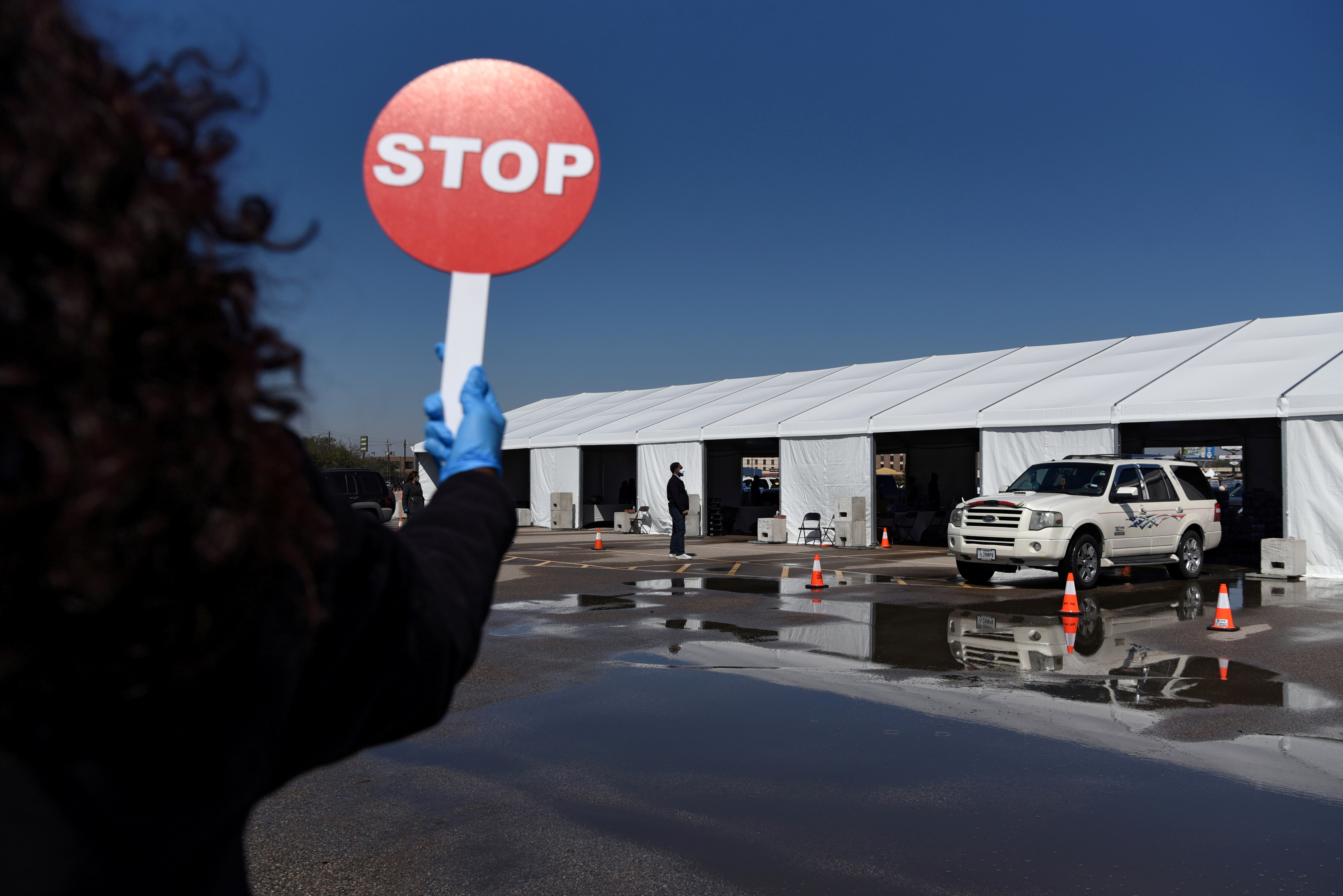A volunteer directs traffic as hundreds of cars line up to receive free cases of water after the city of Houston implemented a boil water advisory following an unprecedented winter storm, at Delmar Stadium in Houston, Texas, U.S., February 19, 2021.  REUTERS/Callaghan O'Hare