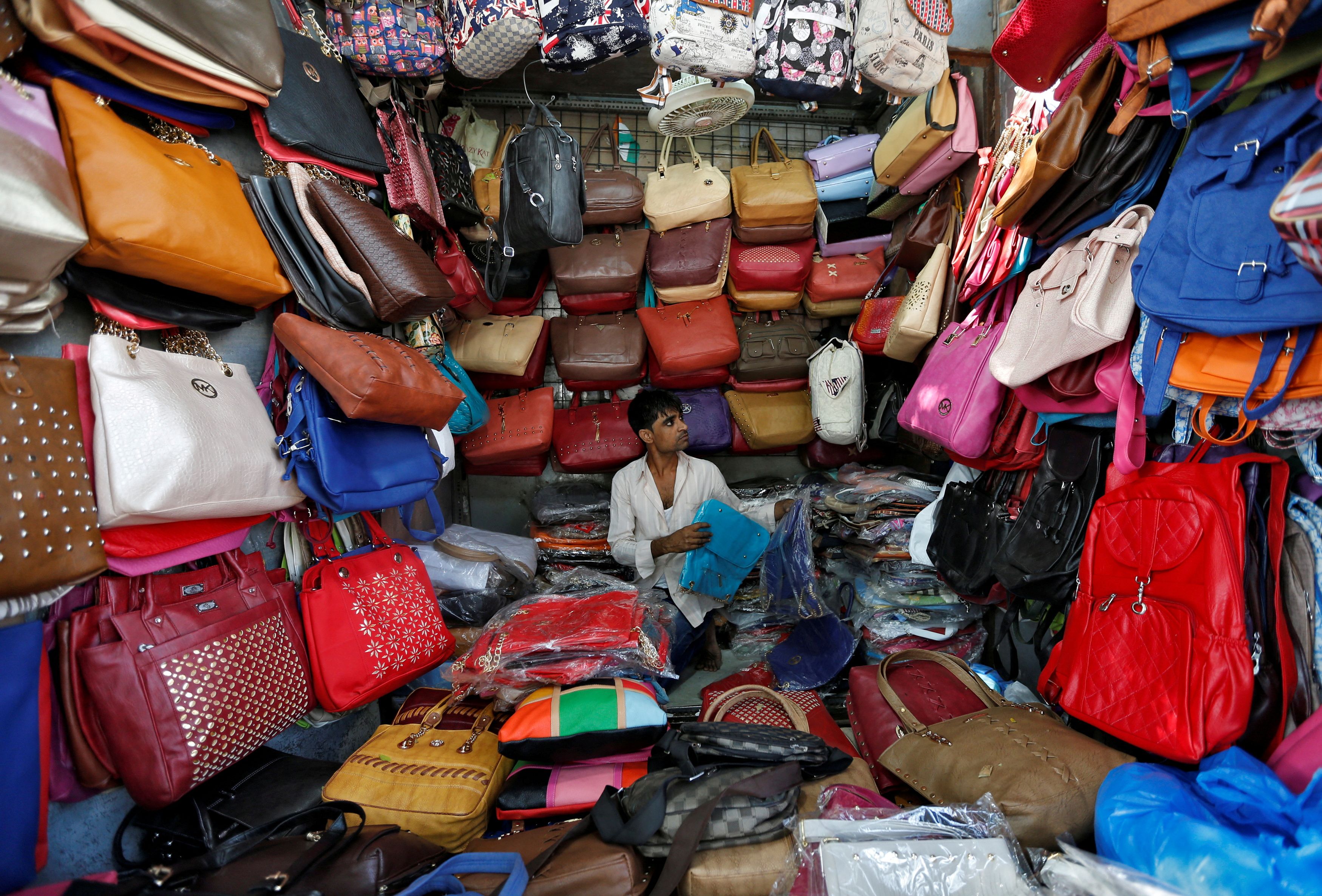 A vendor arranges bags as he waits for customers at his shop at a market in Mumbai