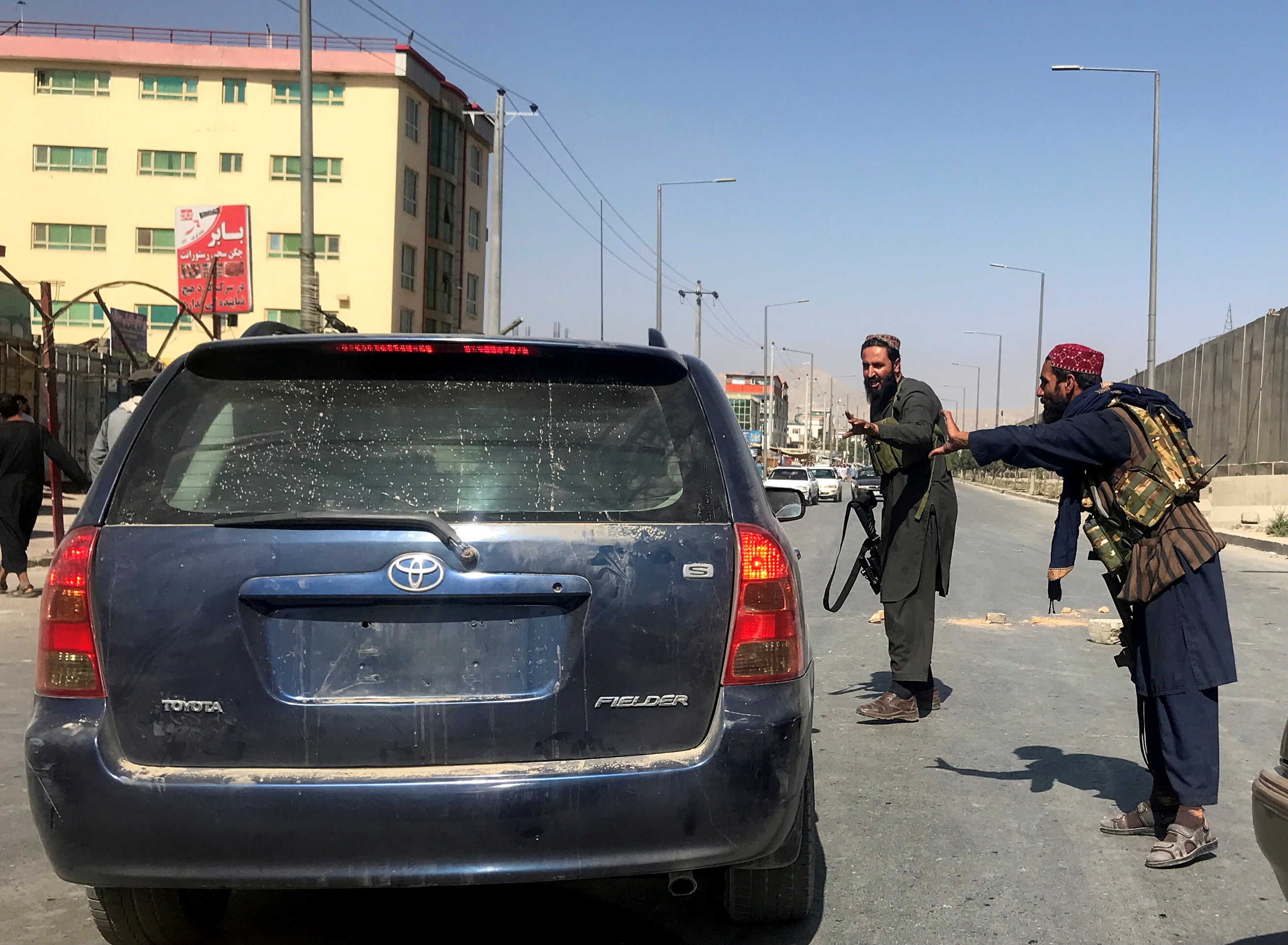 Members of Taliban forces gesture as they check a vehicle in Kabul