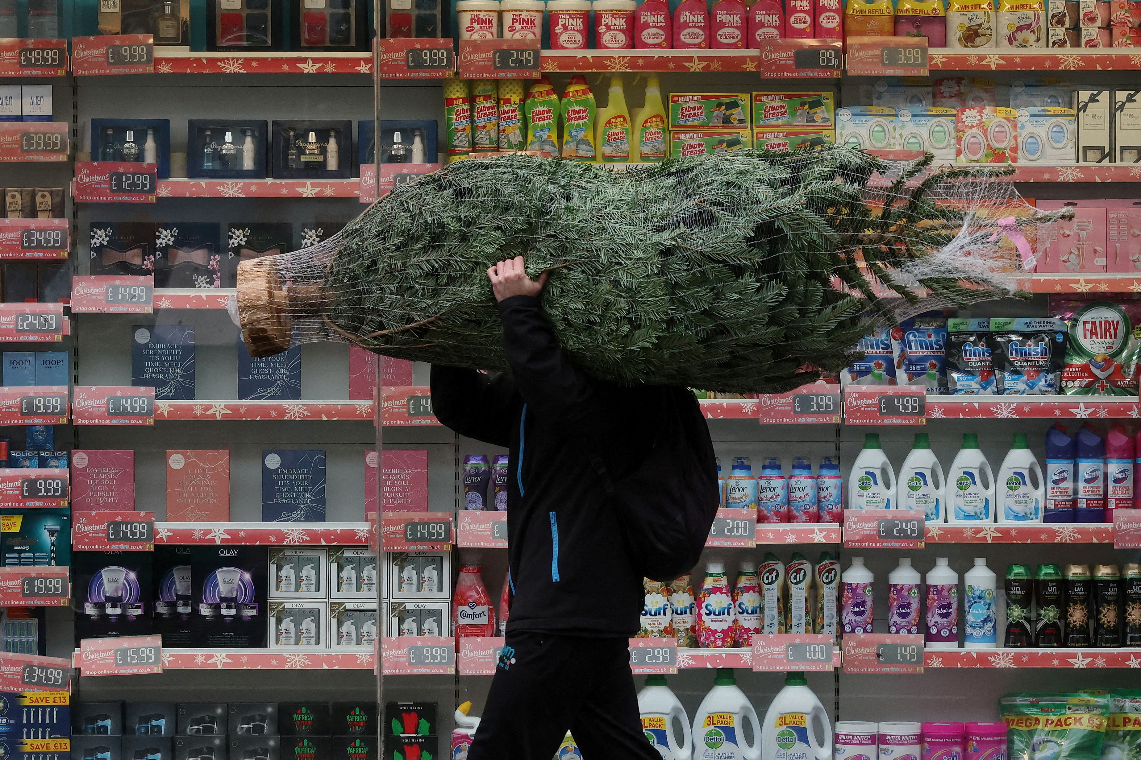 A man carries a Christmas tree amid the coronavirus disease (COVID-19) outbreak, in Fulham, London, Britain December 24, 2021. REUTERS/Kevin Coombs 